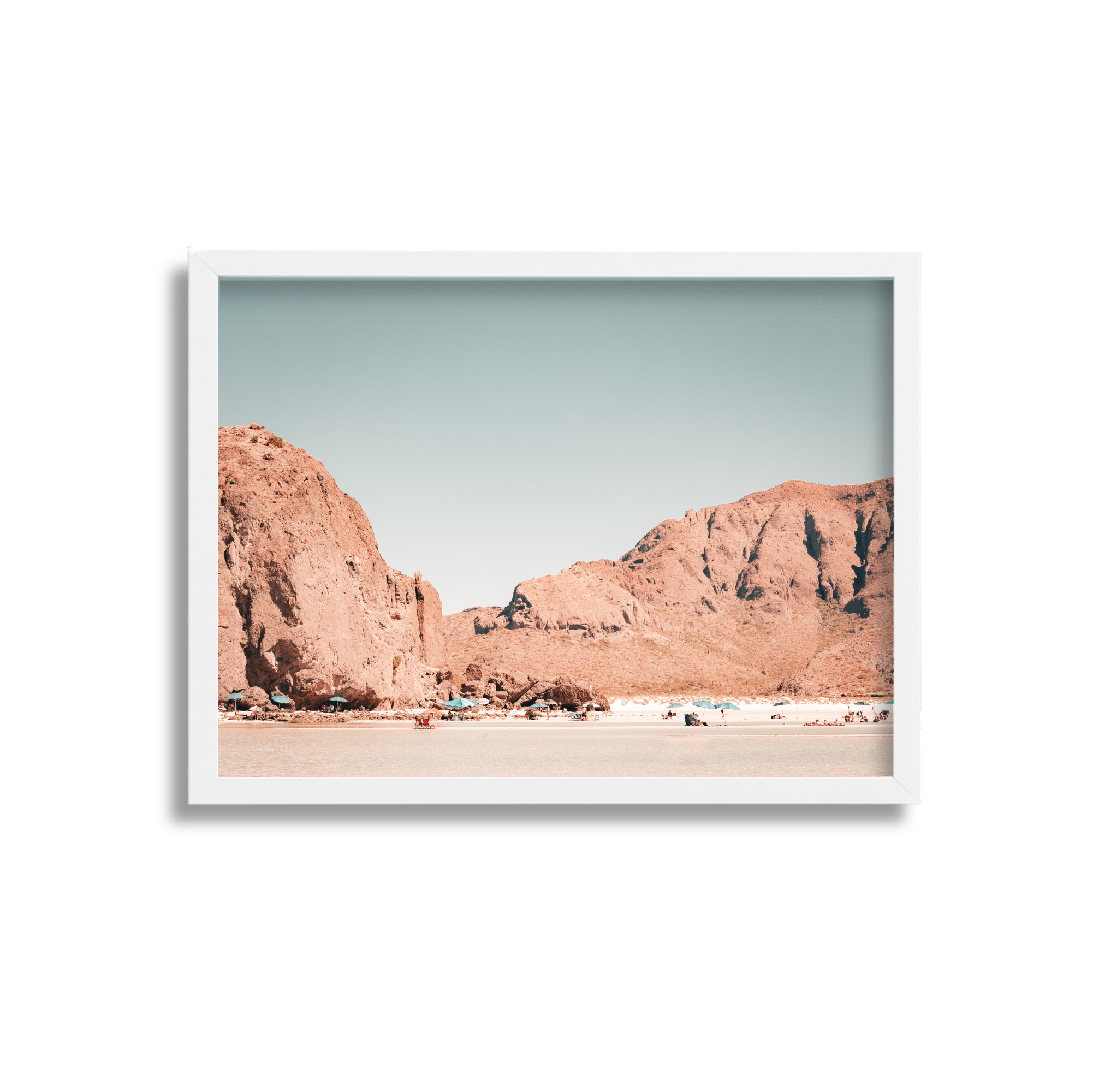A framed photograph of a desert landscape with large reddish-brown rocks and mountains, a flat sandy foreground, and a clear sky