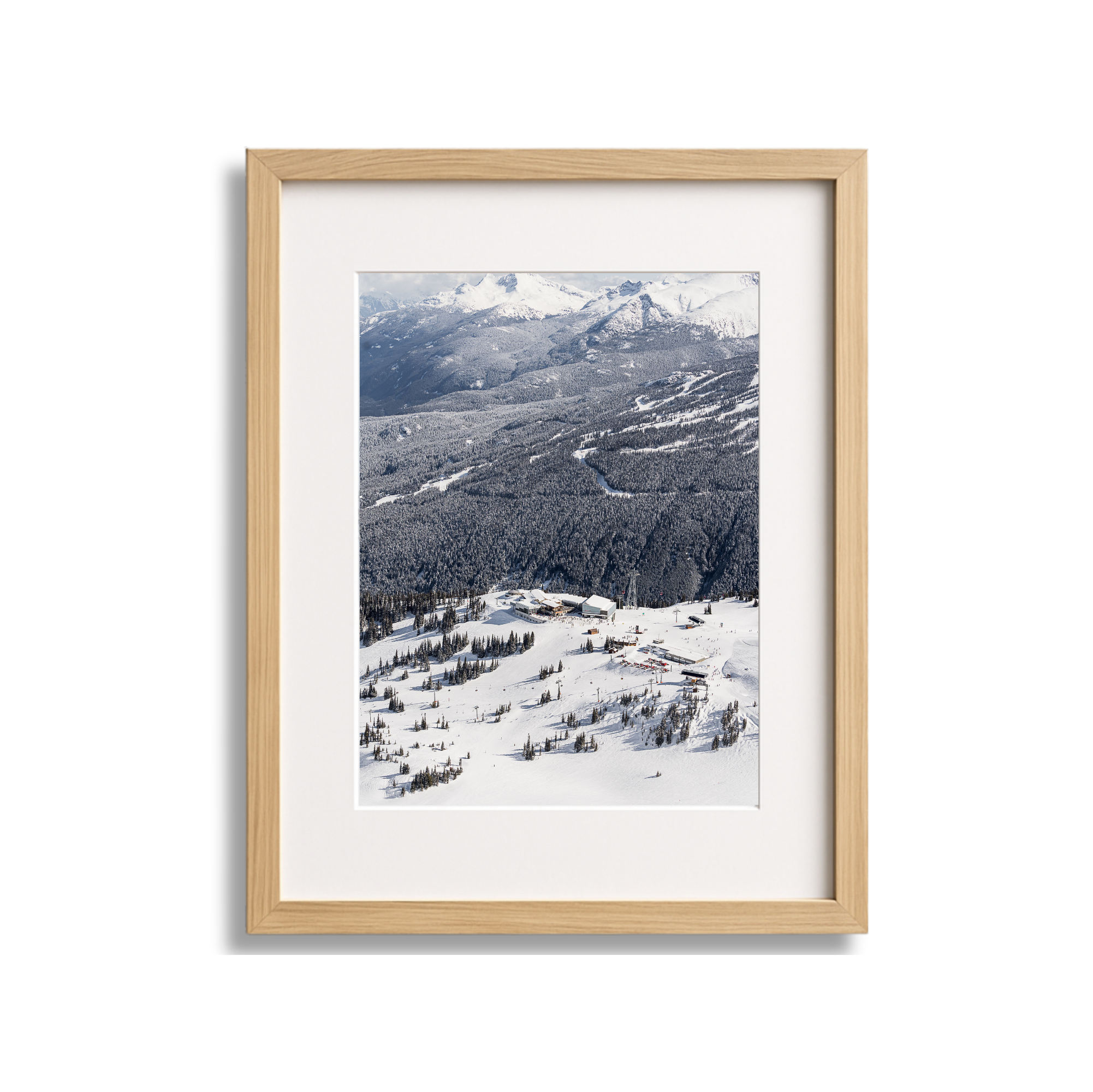 Framed photograph of a snowy mountain landscape with ski resort buildings and trees.