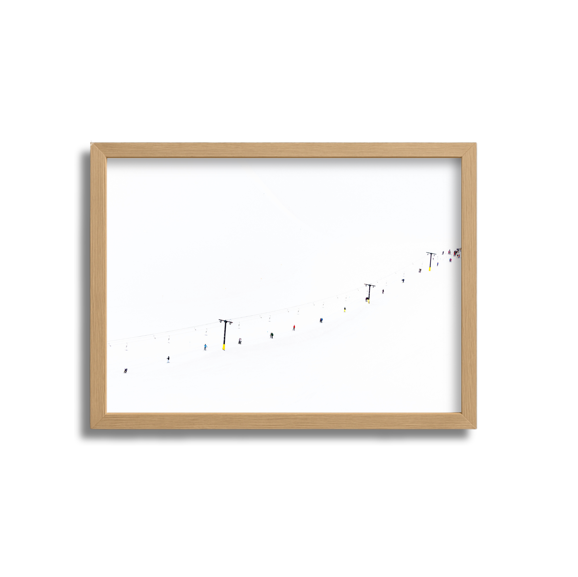 A framed photo of a ski slope with ski lifts and small skiers descending through snow on a foggy day.