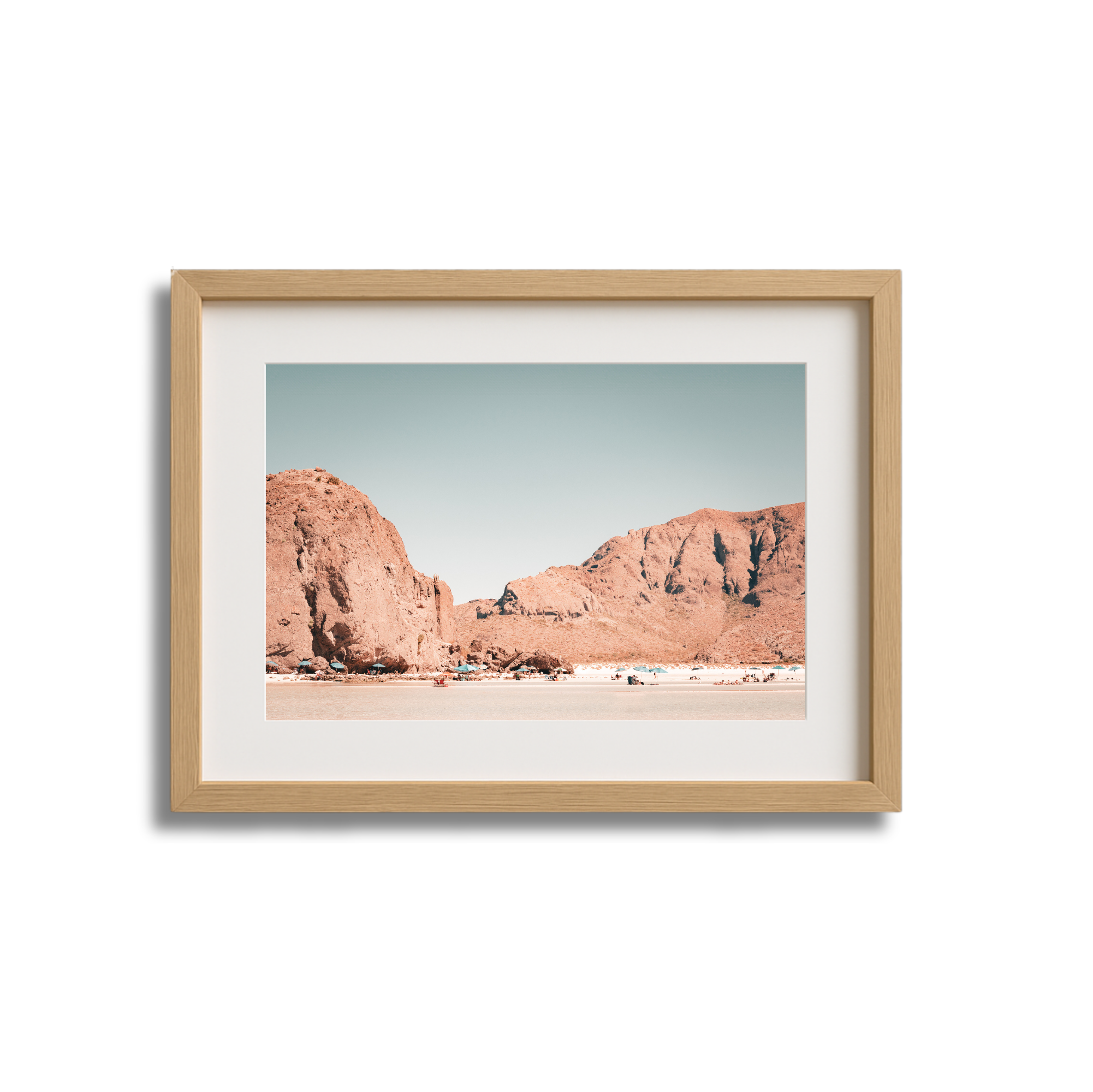 Framed print of a desert landscape with large reddish rock formations against a clear blue sky.