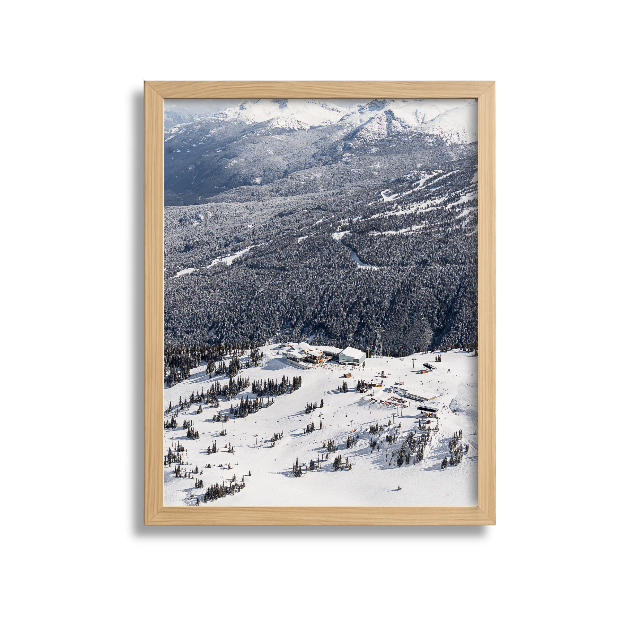 Snow-covered ski resort with buildings, ski lifts, and trees in a mountainous landscape.