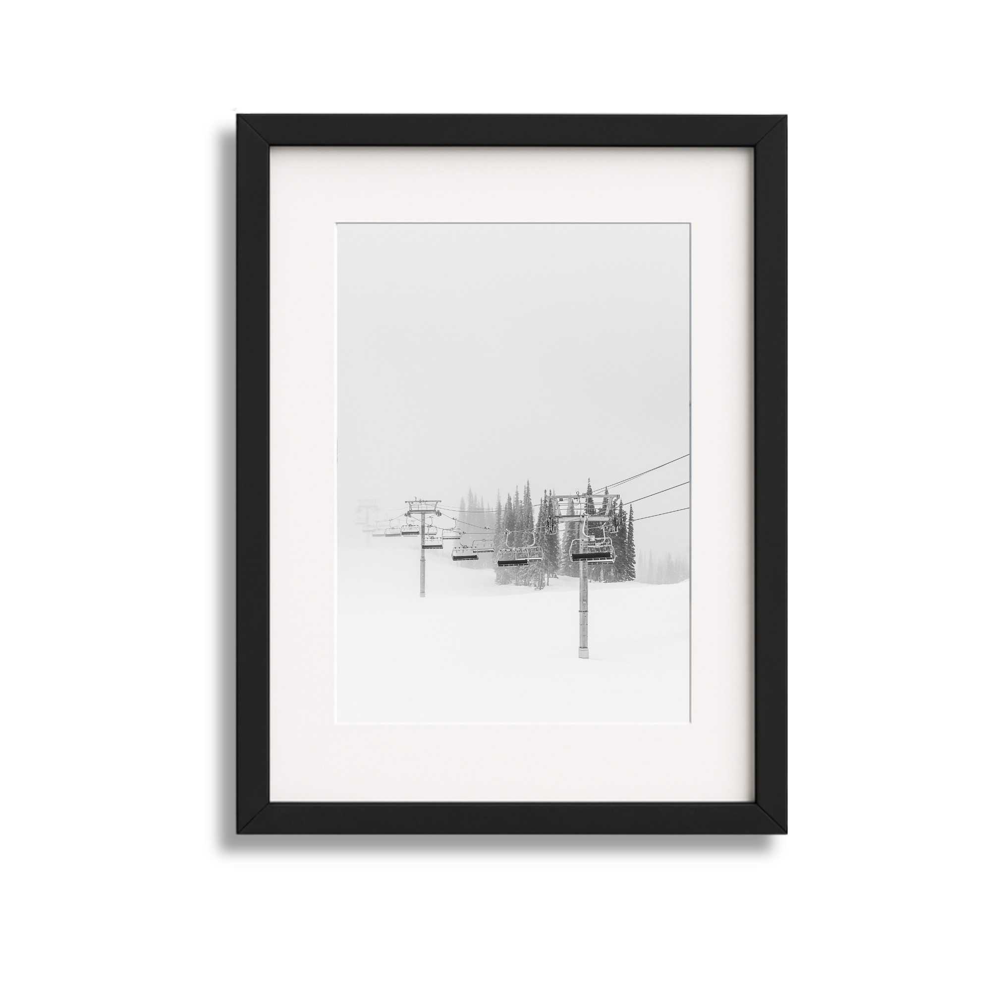 Black frame picture of a snowy ski lift with trees in the background