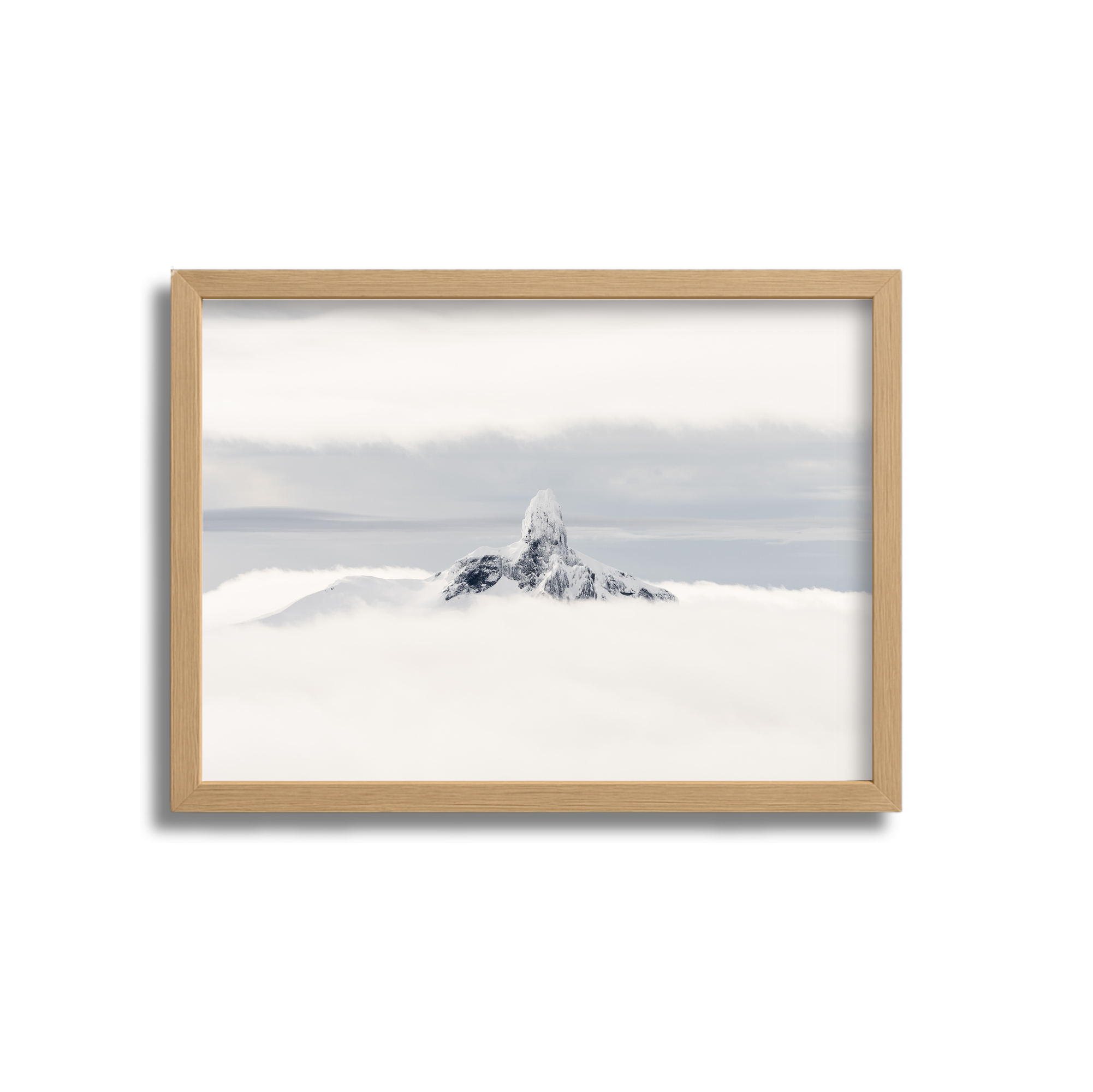 Photograph of a snow-covered mountain peak emerging above a sea of clouds, with a wooden frame.
