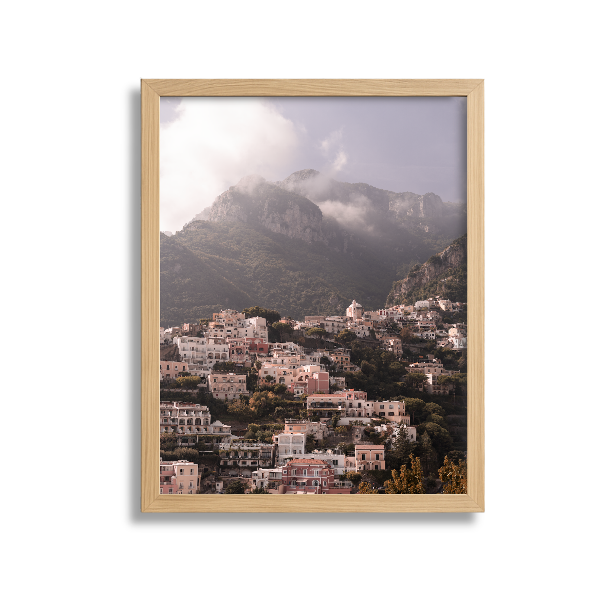 Landscape of a hillside town with white and pastel-colored buildings under a mountain with clouds.