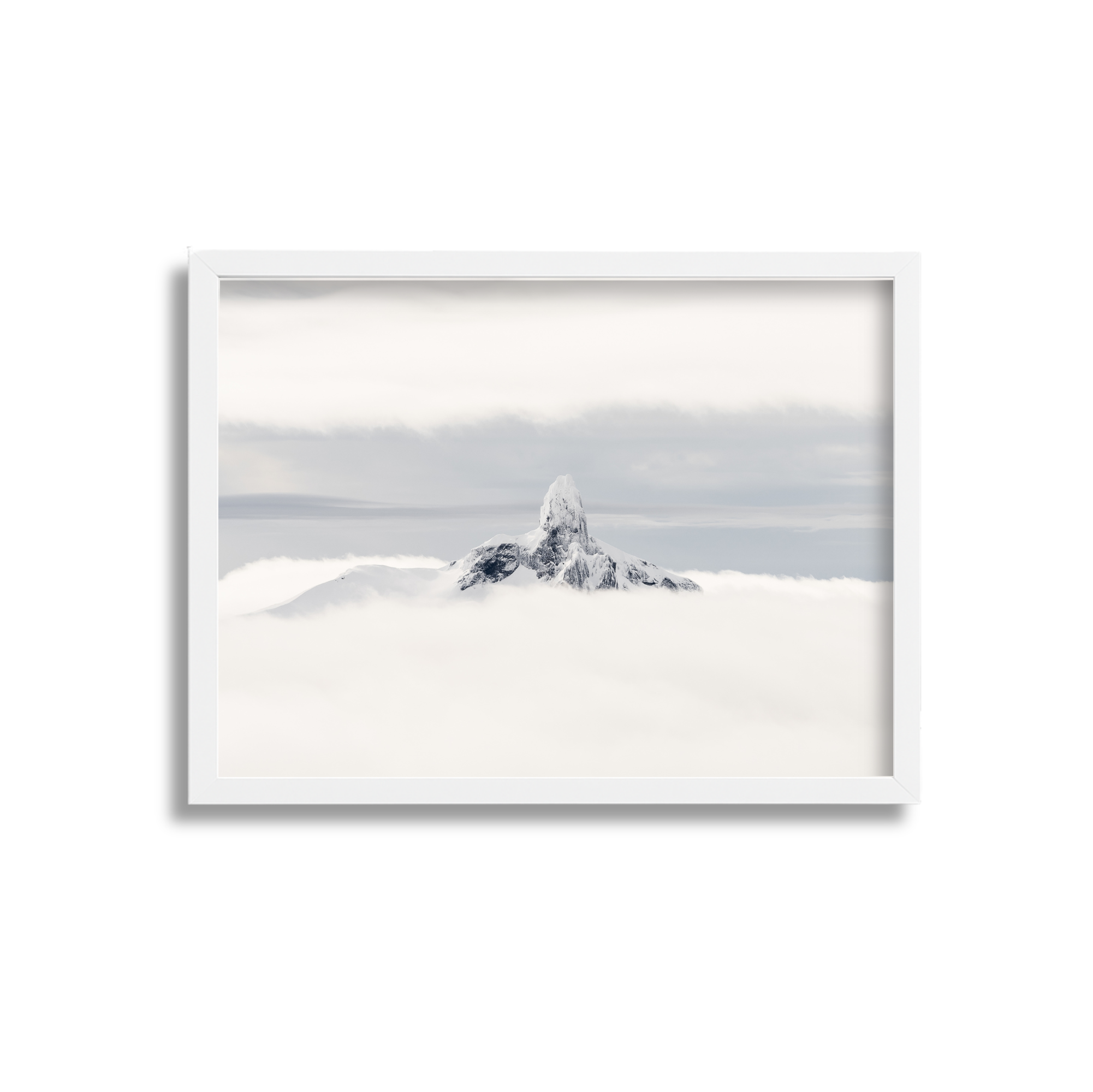 Snow-covered mountain peak rising above a sea of clouds in a white framed picture