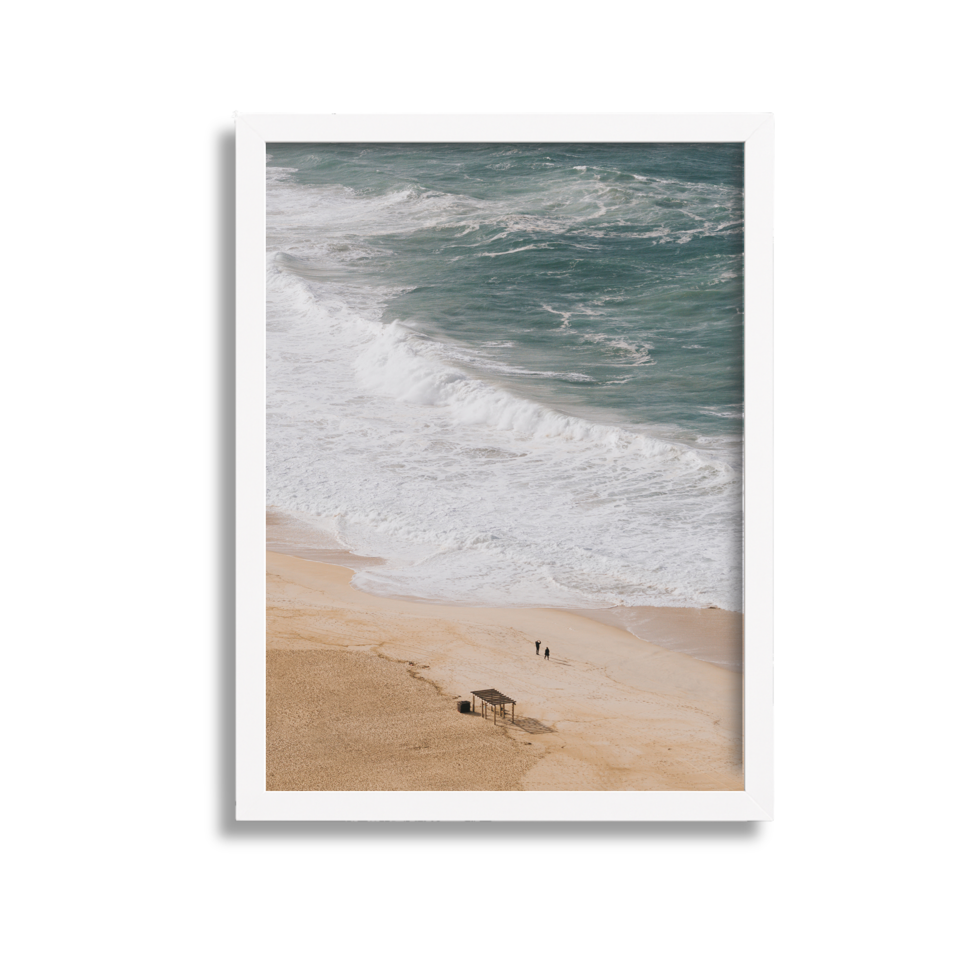 Photograph of a beach with waves crashing on the shore, two people walking, and a small shelter on the sand.