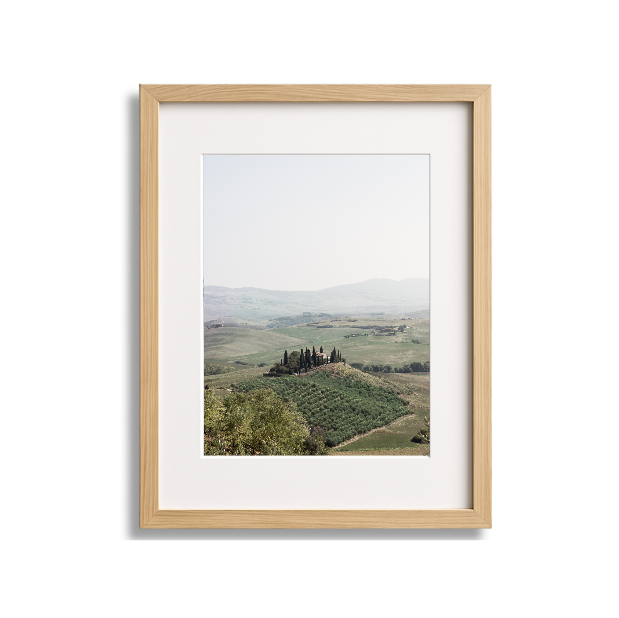 Framed landscape photograph of rolling hills, trees, and distant mountains.