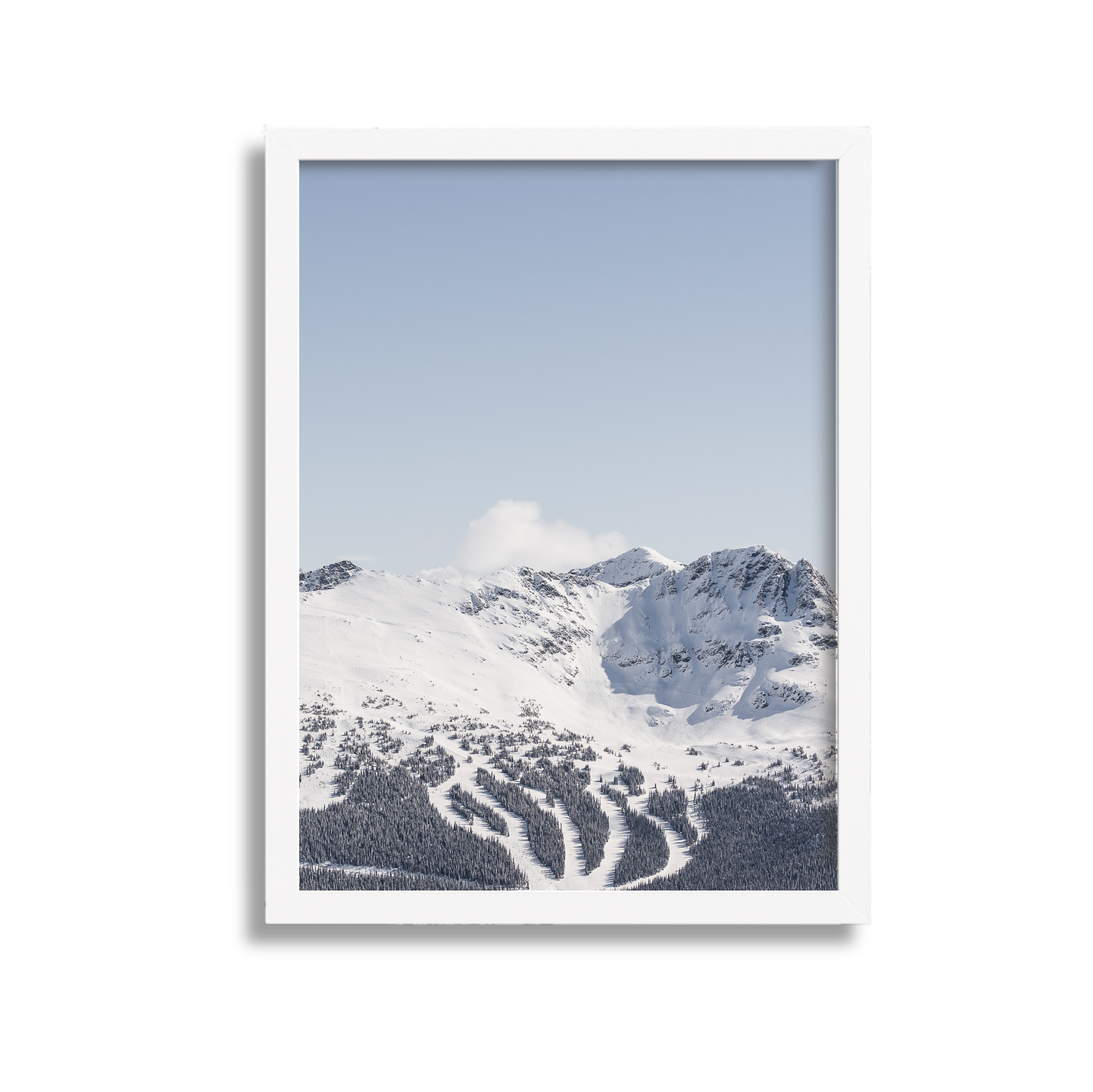 Framed photograph of snow-covered mountains and ski slopes with a clear blue sky.