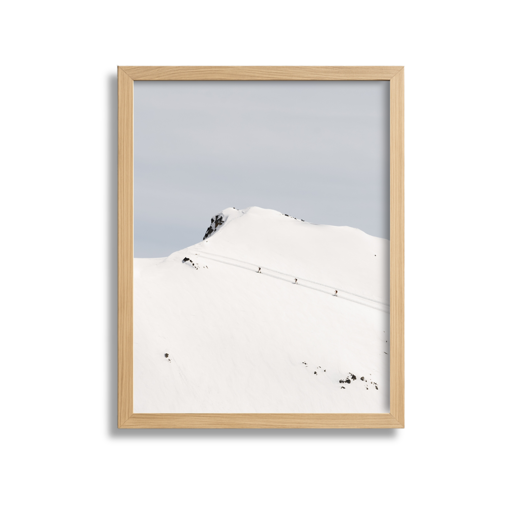Snow-covered mountain with a few climbers and a rocky peak in the background.