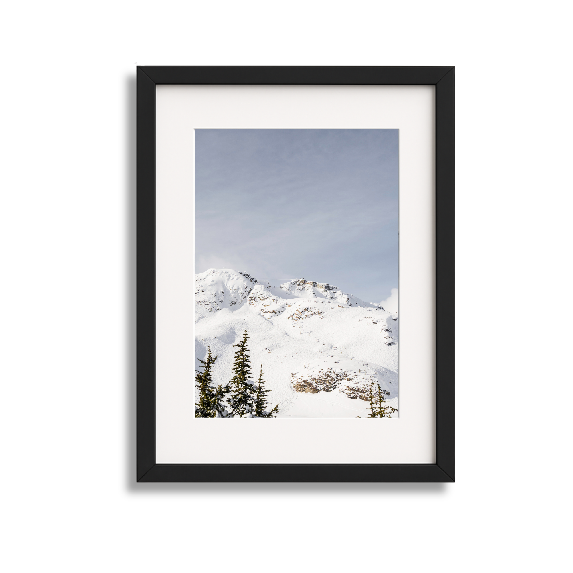 Framed photograph of snow-covered mountains with pine trees in the foreground under a partly cloudy sky.
