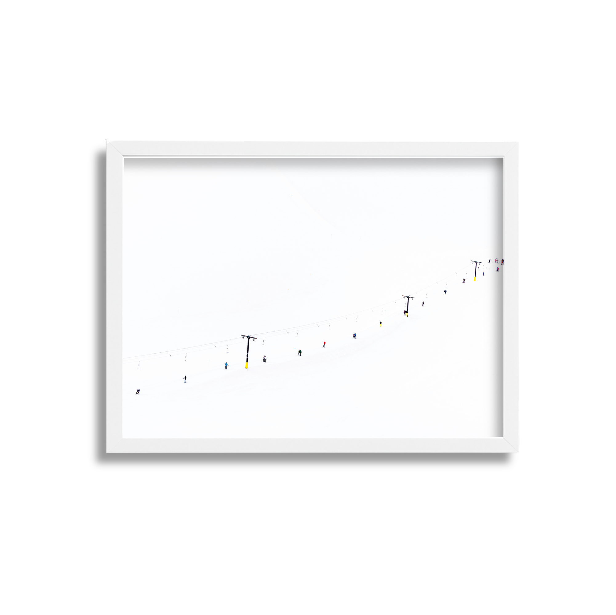 Ski lift cables and chairs with small colored skiers and snowboarders on a snow-covered mountain under a white sky.