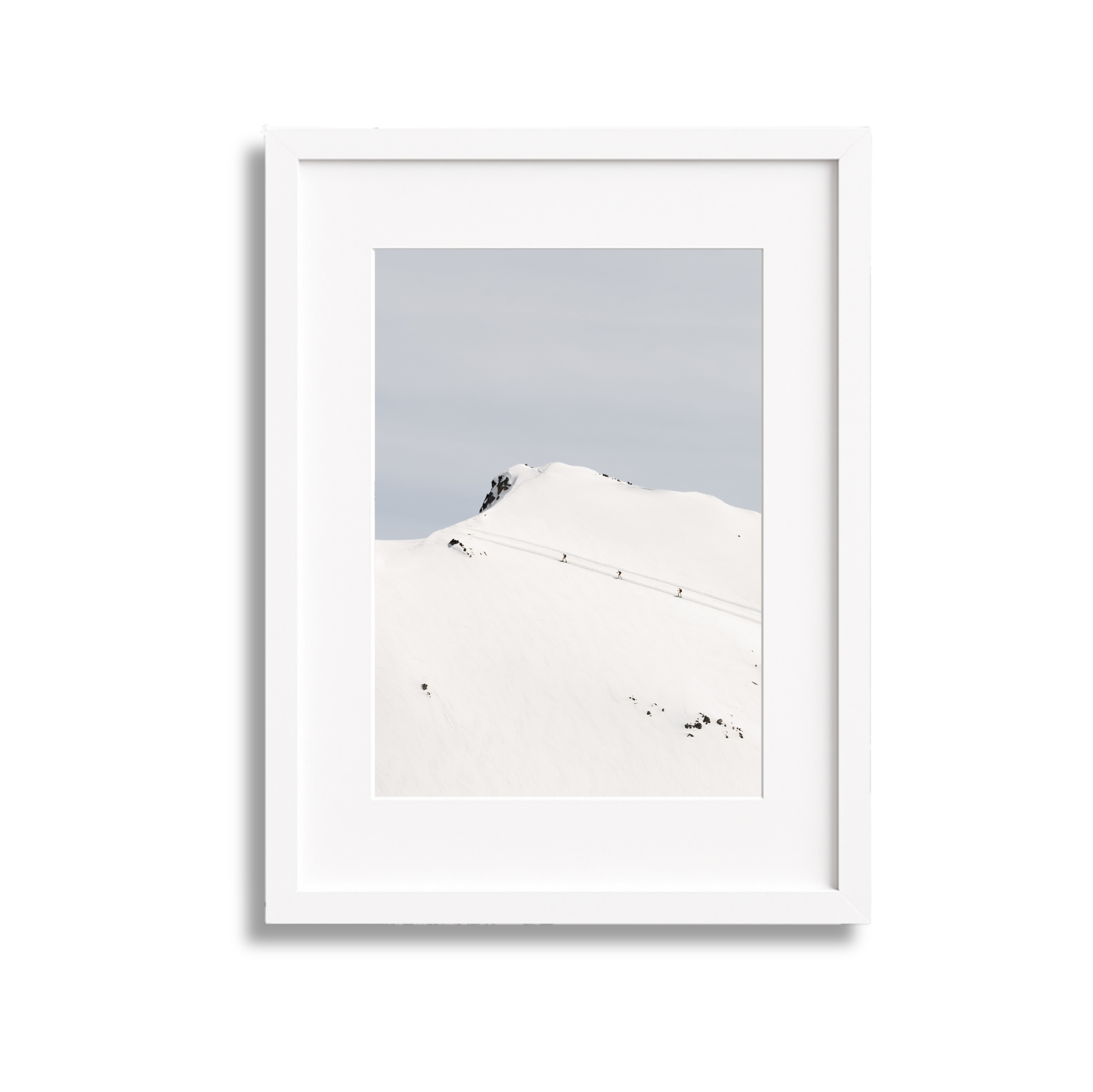 Snow-covered mountain with a few climbers, rocky peak, and cloudy sky.