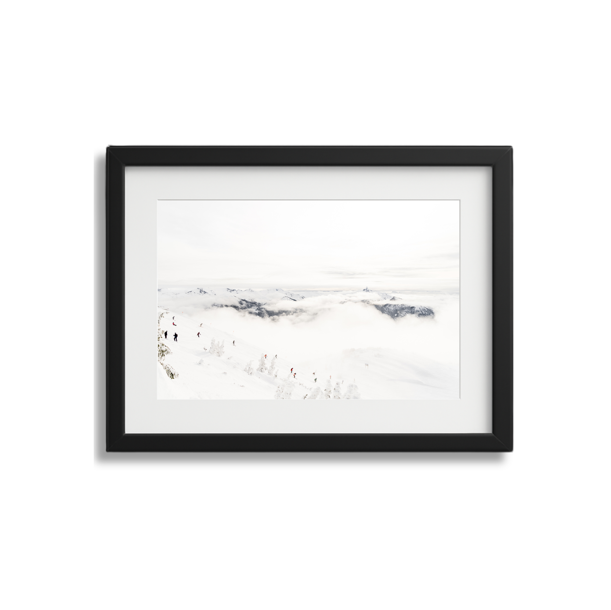 Framed photograph of snowy mountain landscape with skiers and a cloudy sky.