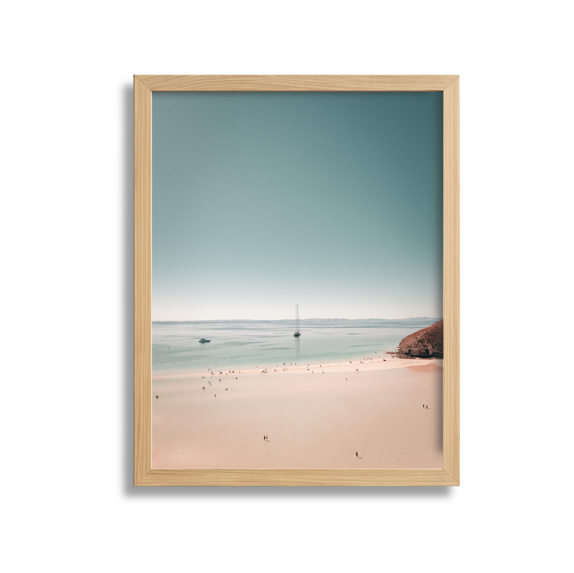 Framed photo of a beach scene with sandy shore, boats in the water, and a blue sky.