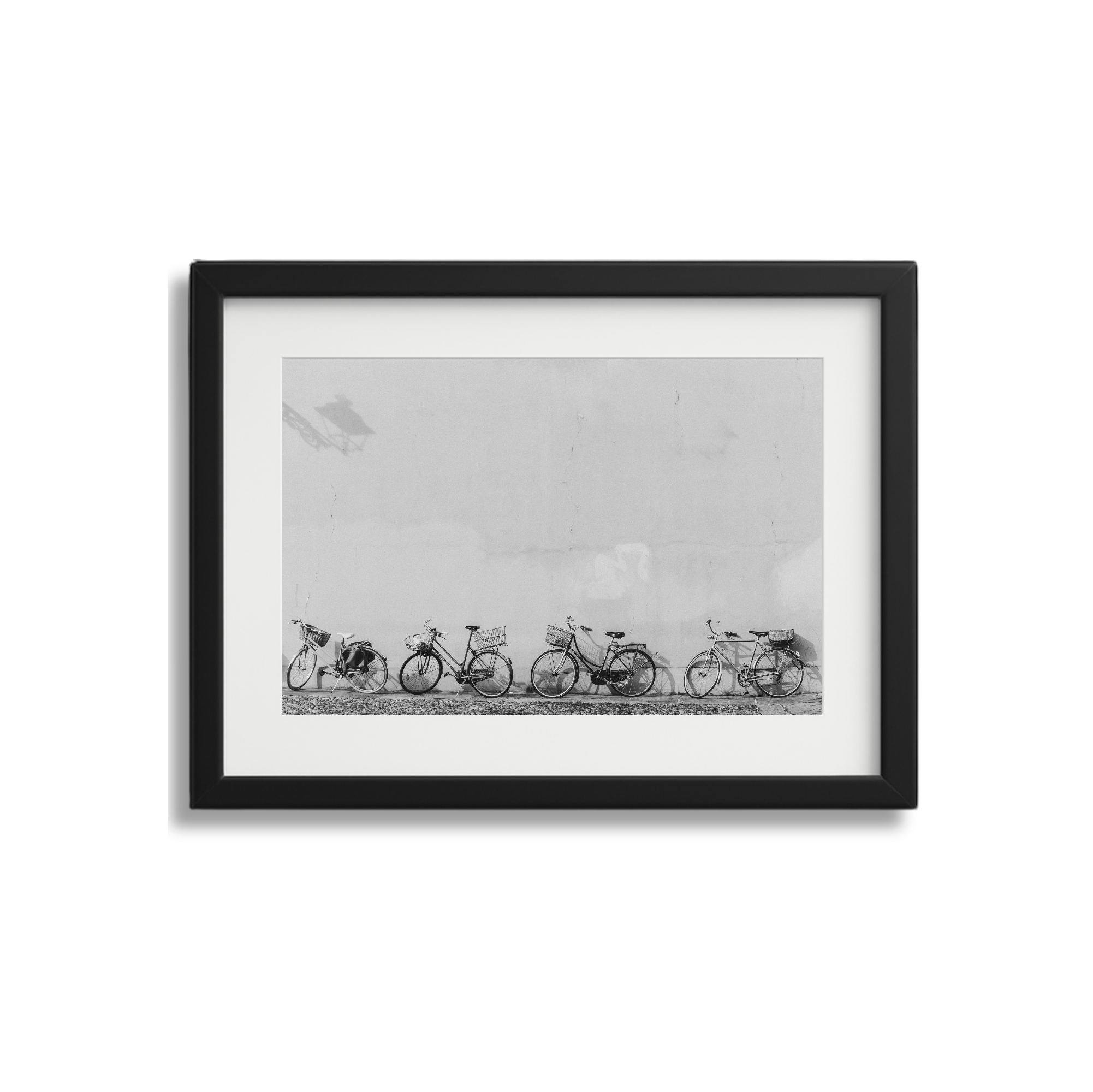 Black and white photo of bicycles lined up, framed and hung on a wall.
