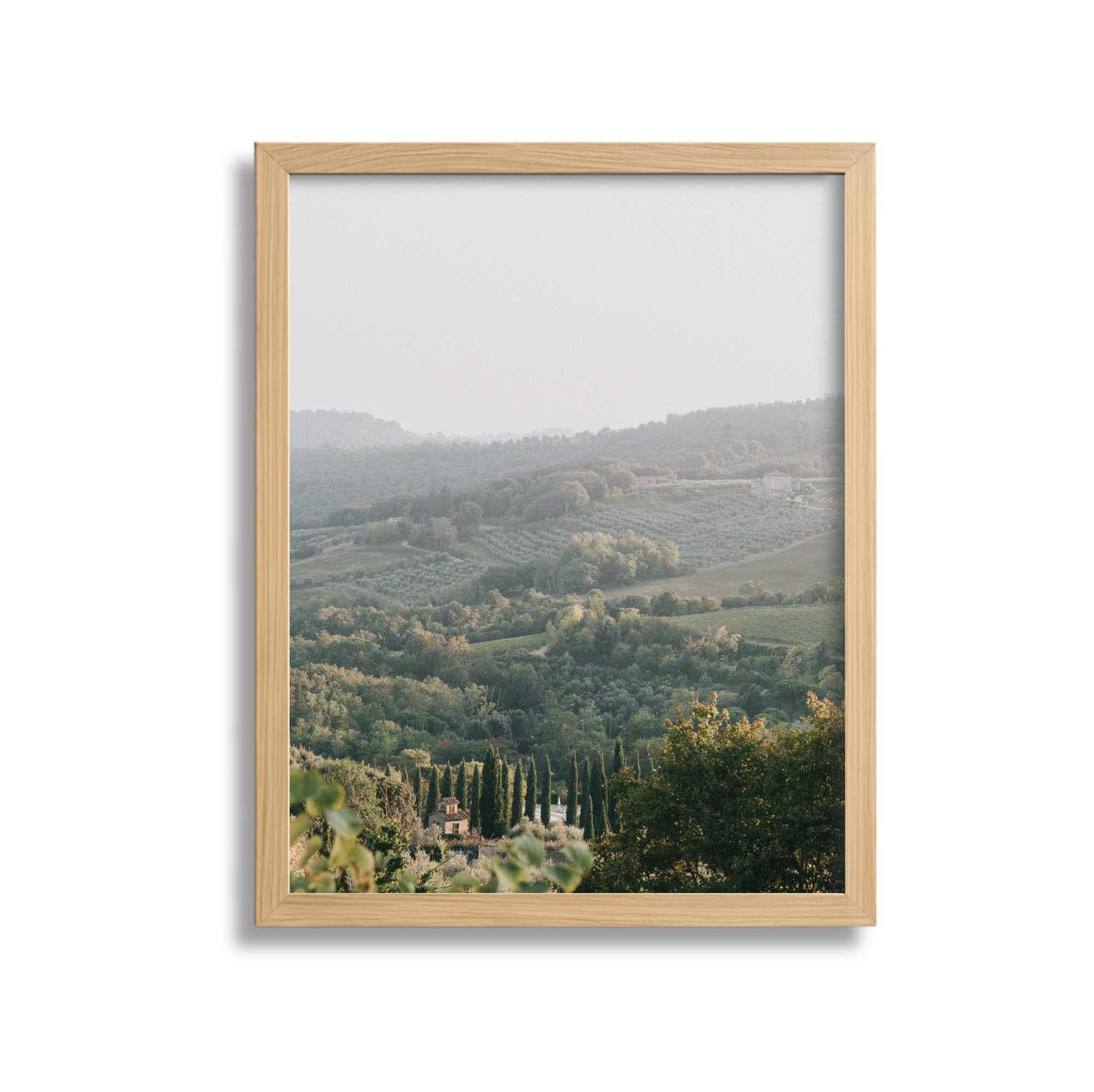 A landscape view of rolling green hills and farmland viewed through a wooden picture frame.