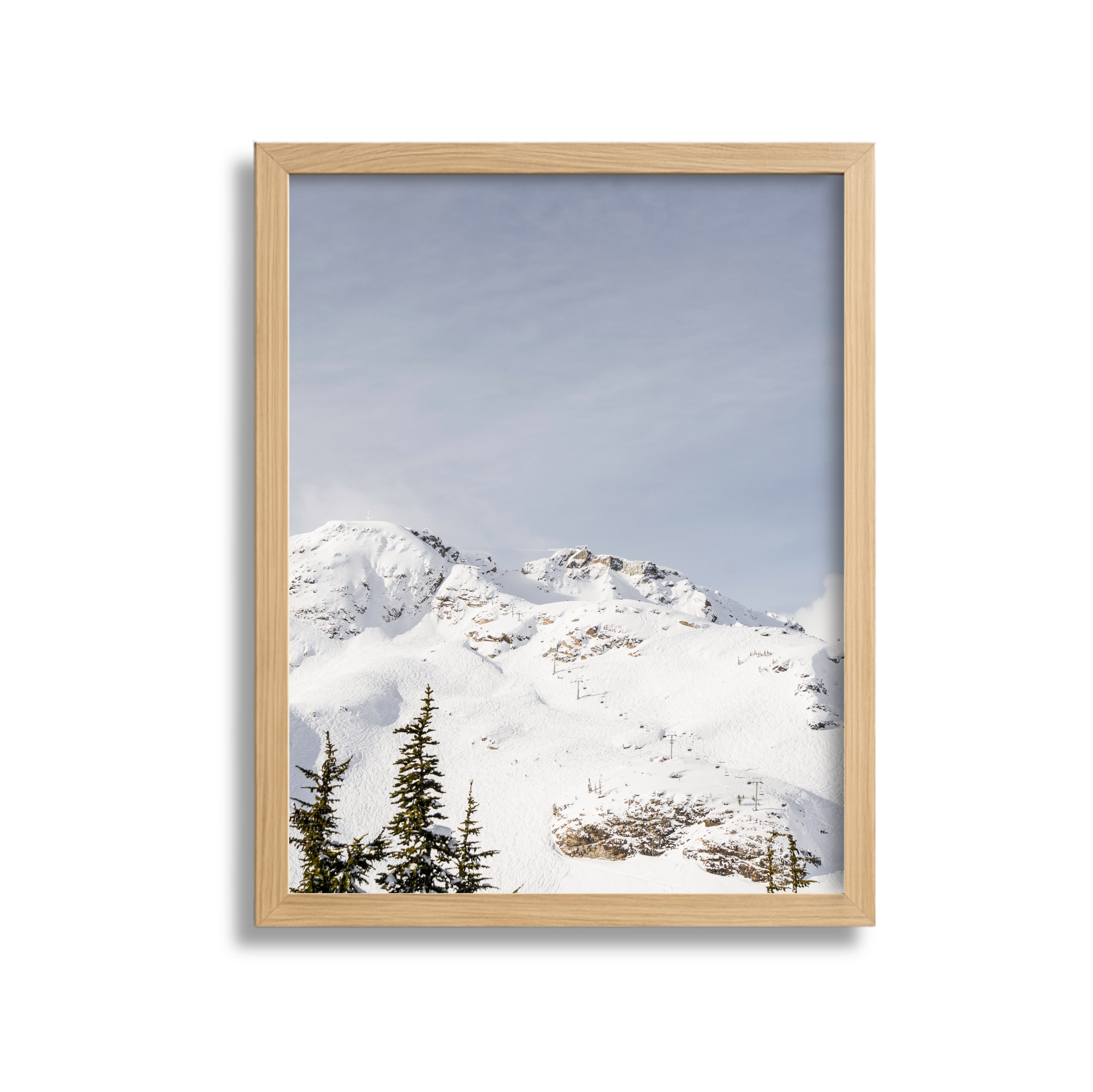 Snow-covered mountain landscape viewed through a wooden picture frame with pine trees in the foreground.