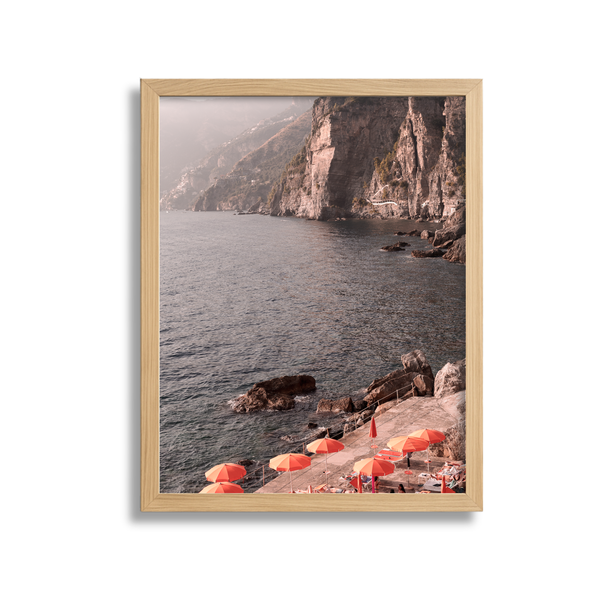 Coastal scene with rocky cliffs, water, and orange umbrellas on a concrete platform.