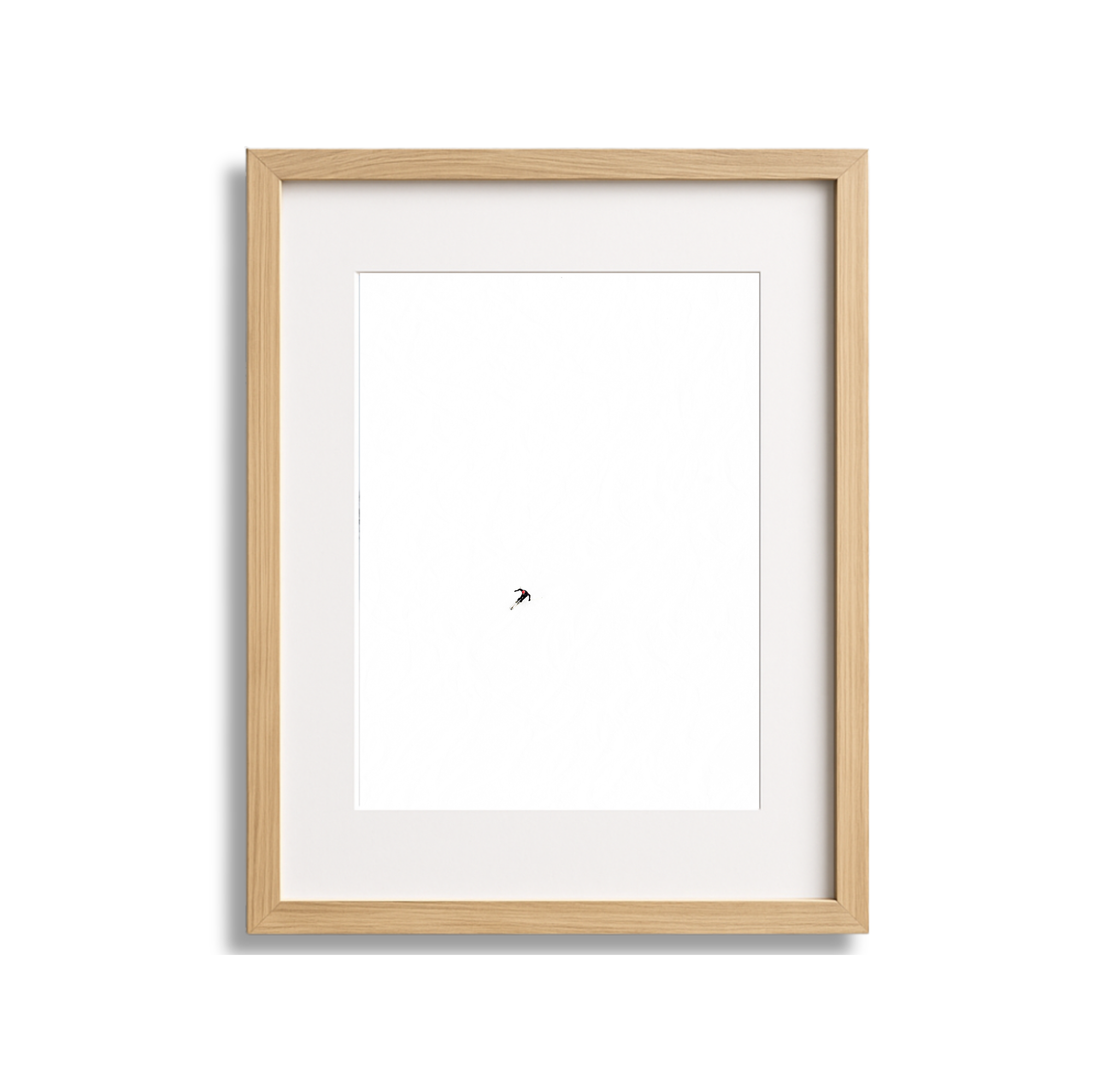 A framed photograph of a single skier descending a snowy slope against a white background.