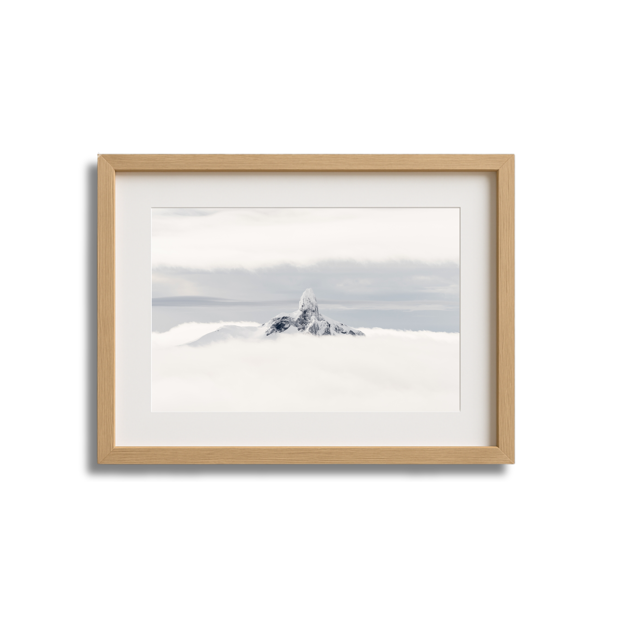 Framed photograph of a snow-capped mountain peak above clouds, with a cloudy sky in the background.