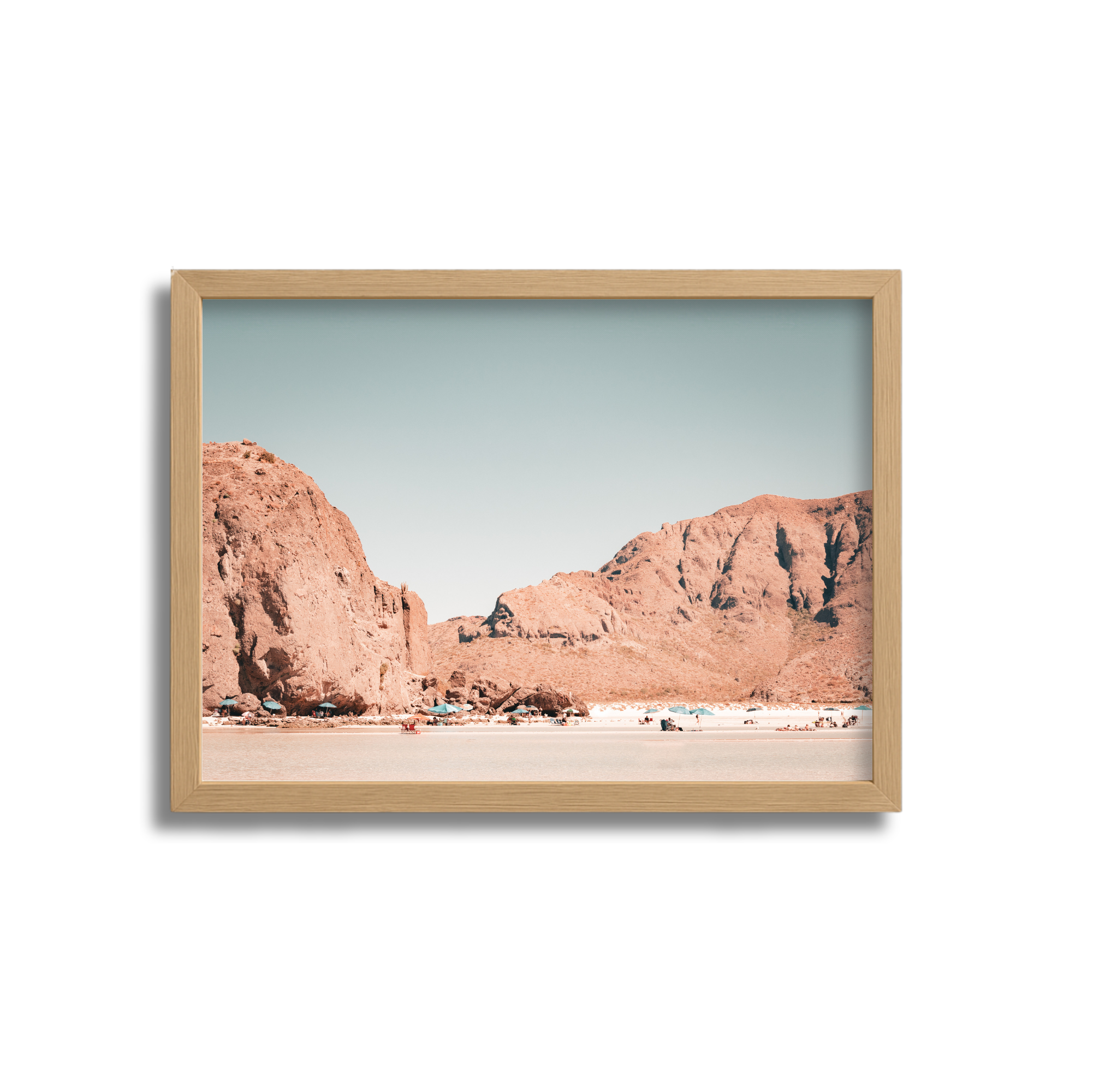 Photography of a desert landscape with rocky mountains and a sandy plain under a clear sky, framed in a wooden picture frame.