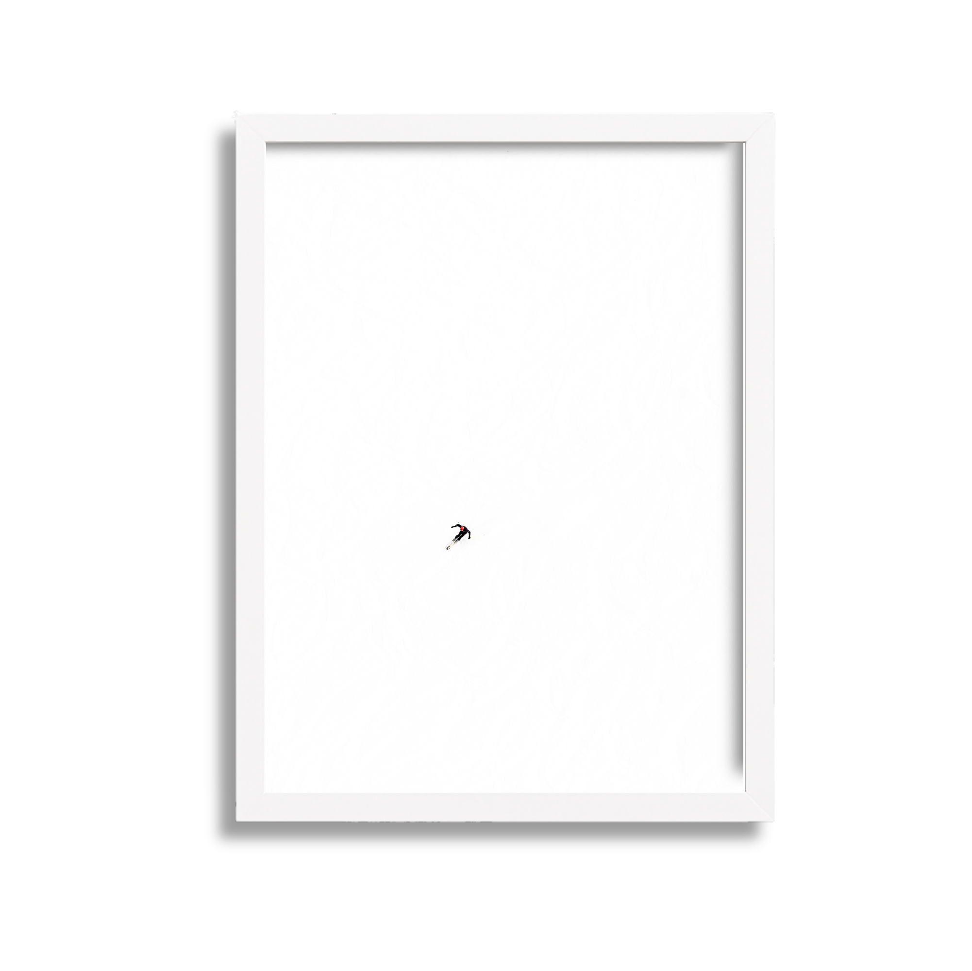 A framed poster with a minimalistic white background and a small figure of a skier descending a snow-covered slope.