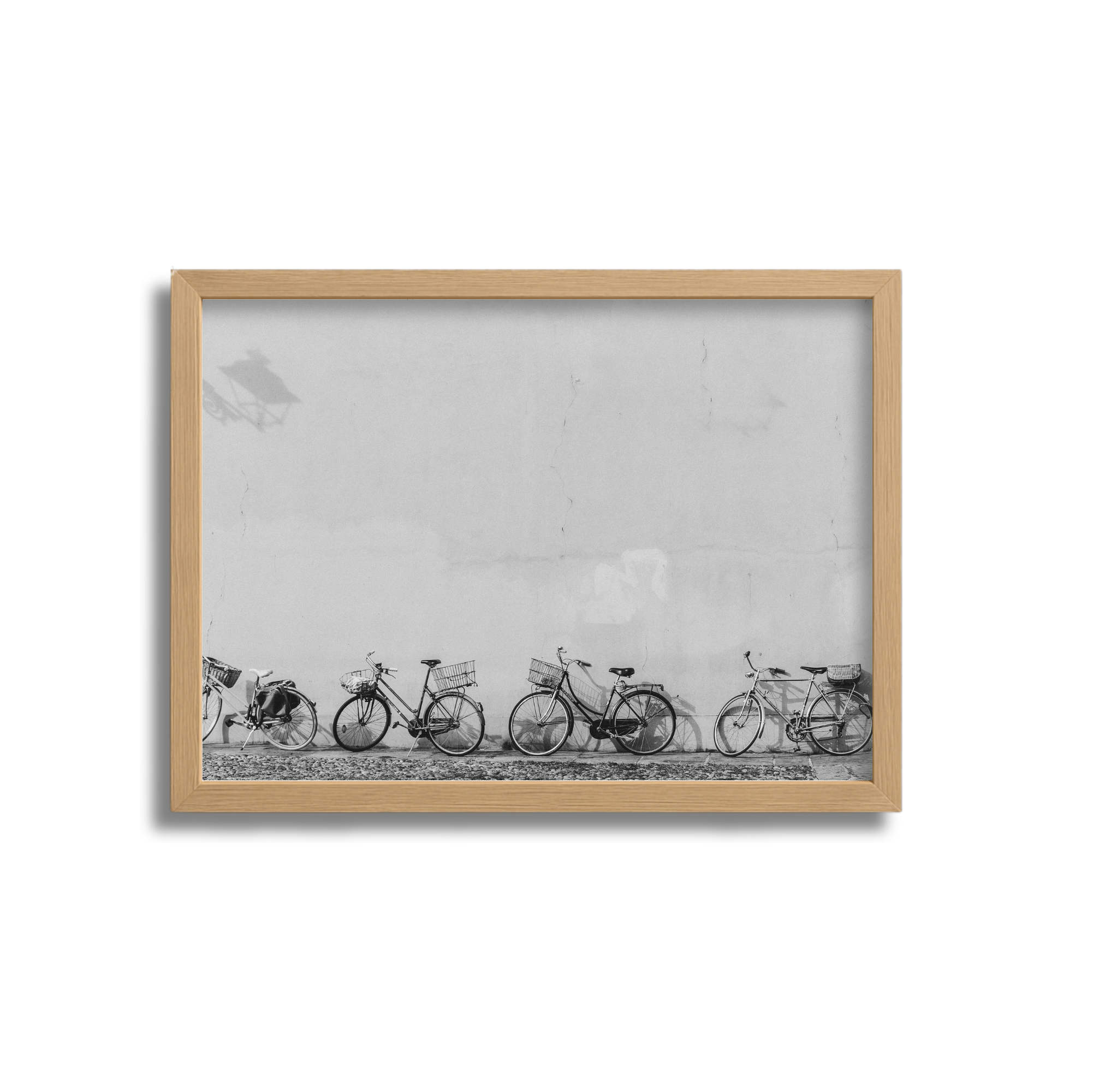 Black and white photograph of multiple bicycles parked against a wall, framed in wood.
