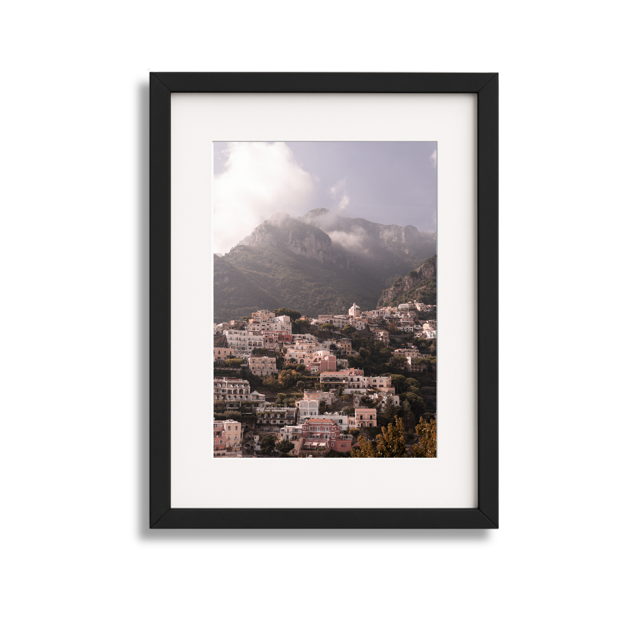 Framed photo of a hillside town with numerous houses on a mountain slope, background featuring mountains and cloudy sky.