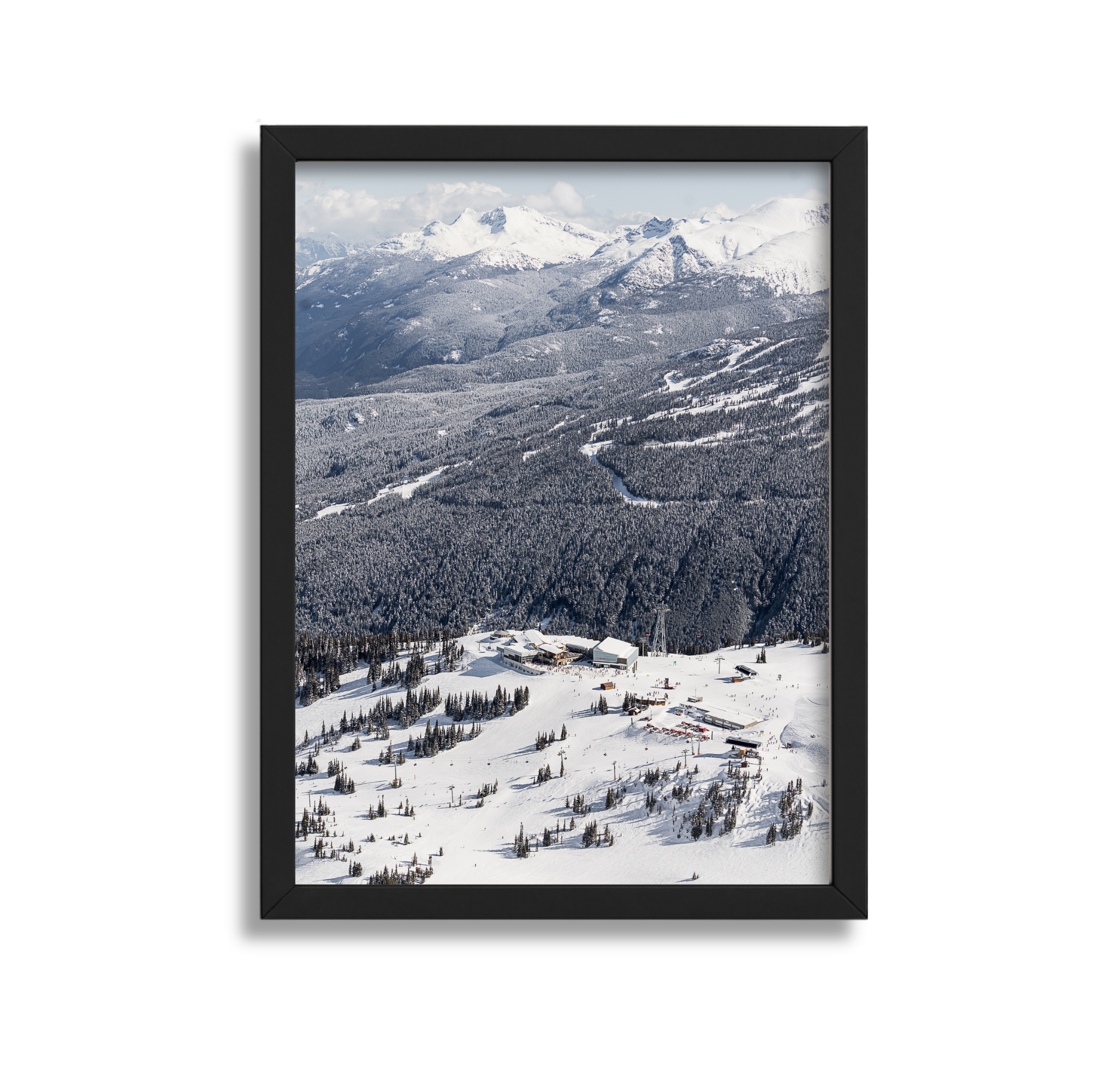 Snow-covered mountains and forest seen through a black picture frame.