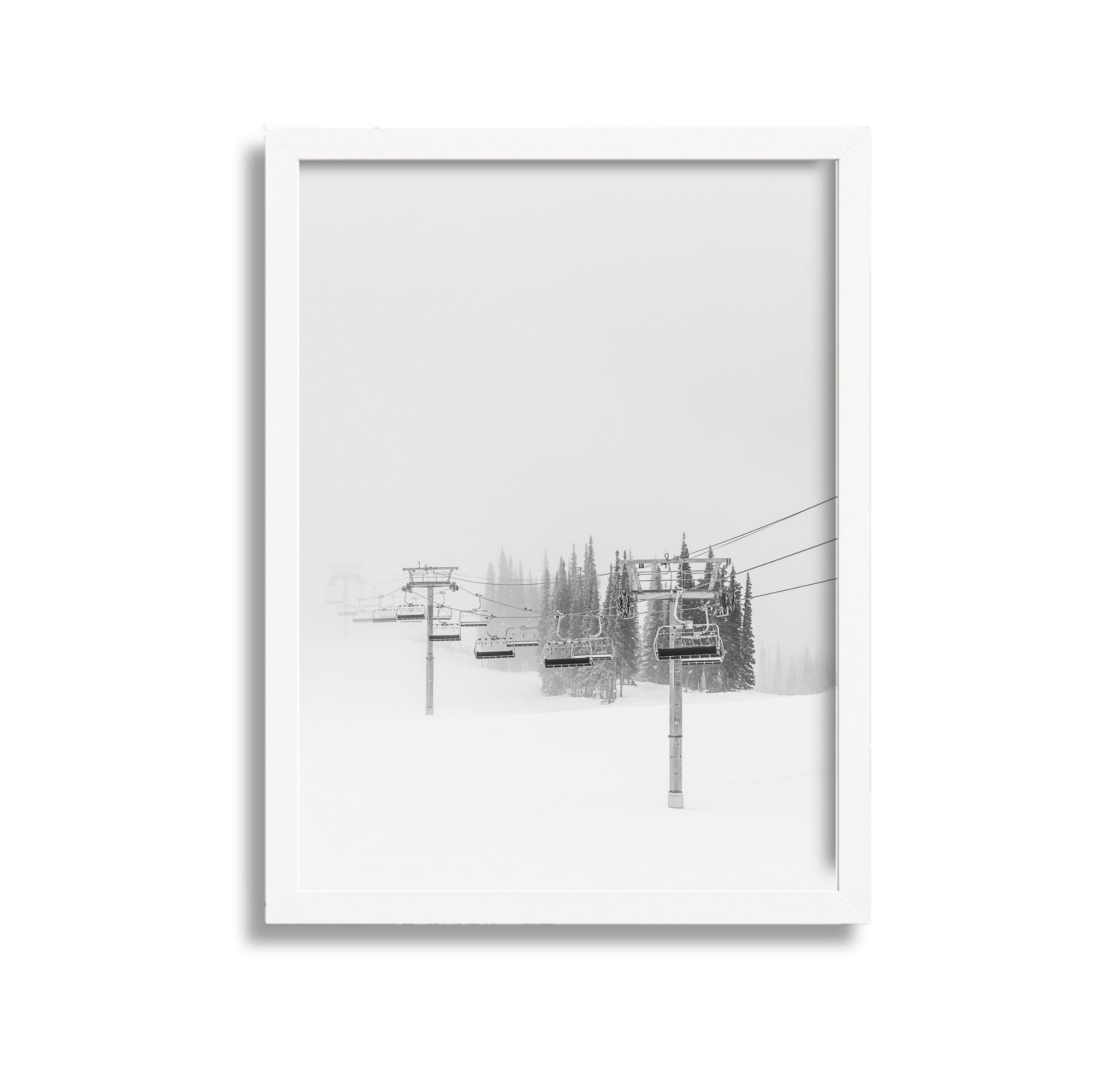 Ski lift chairs on snow-covered ground with foggy background and evergreen trees