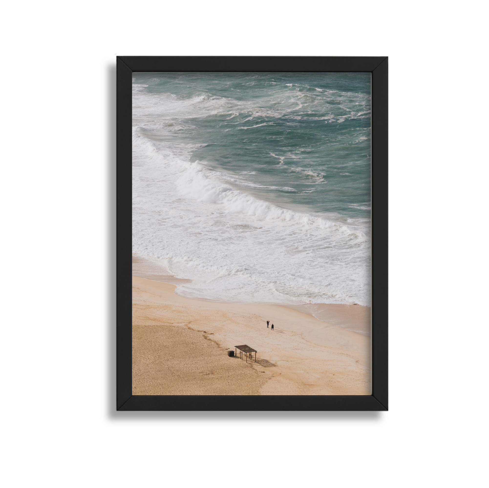 Photo of a beach with waves crashing on the shore, sand, and two small figures walking near a wooden structure.