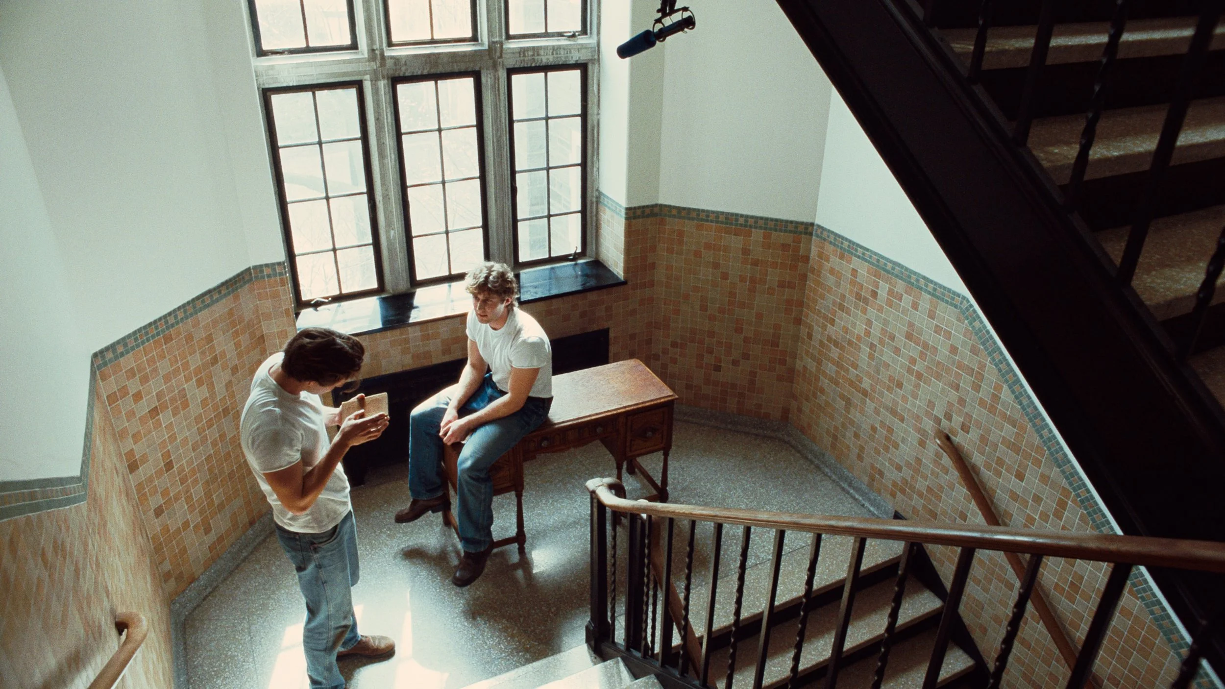 Two boys in a school stairwell reading a book, bleach bypass or cross processed film look
