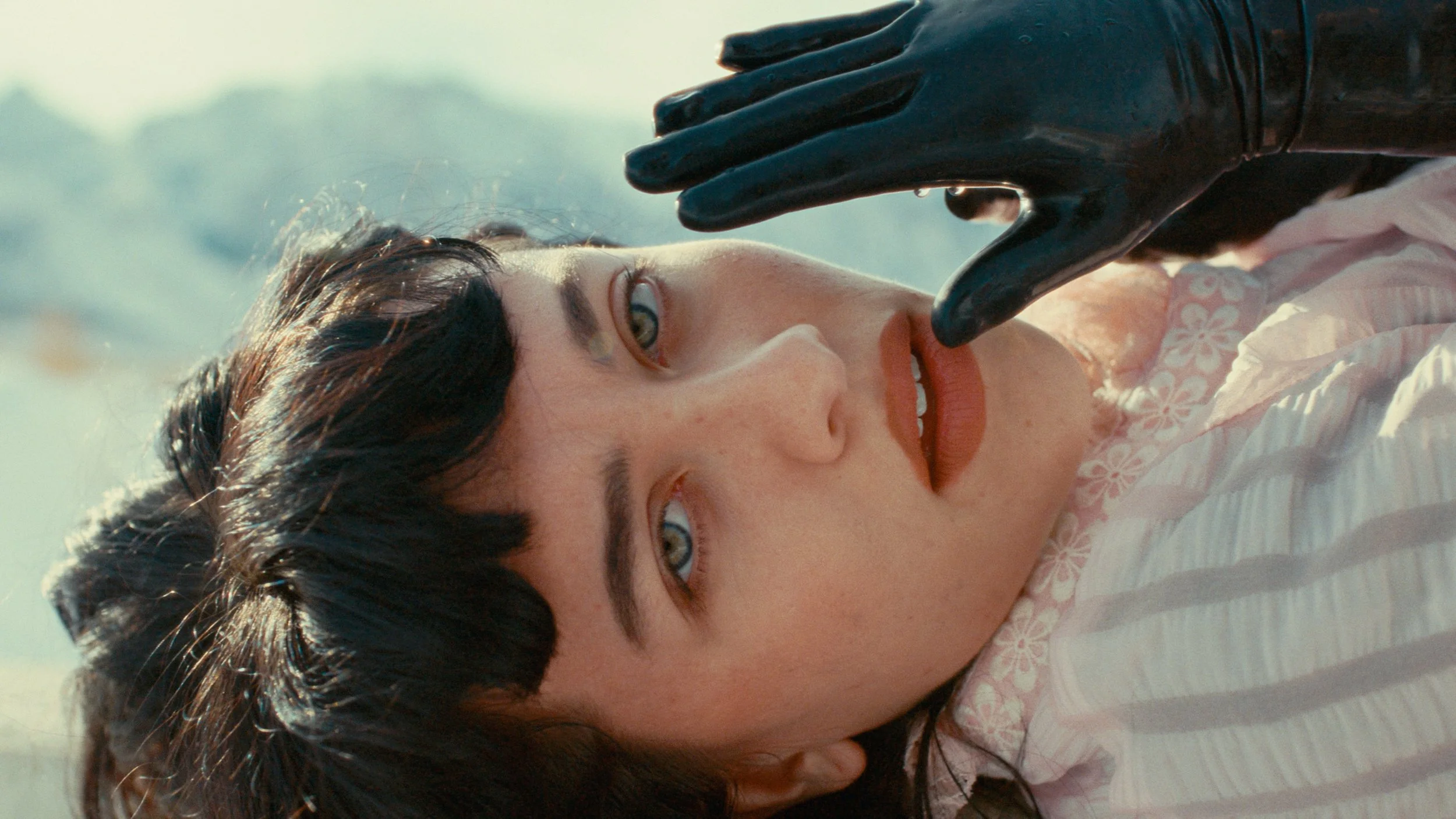 Woman lying down wearing pink dress and black gloves