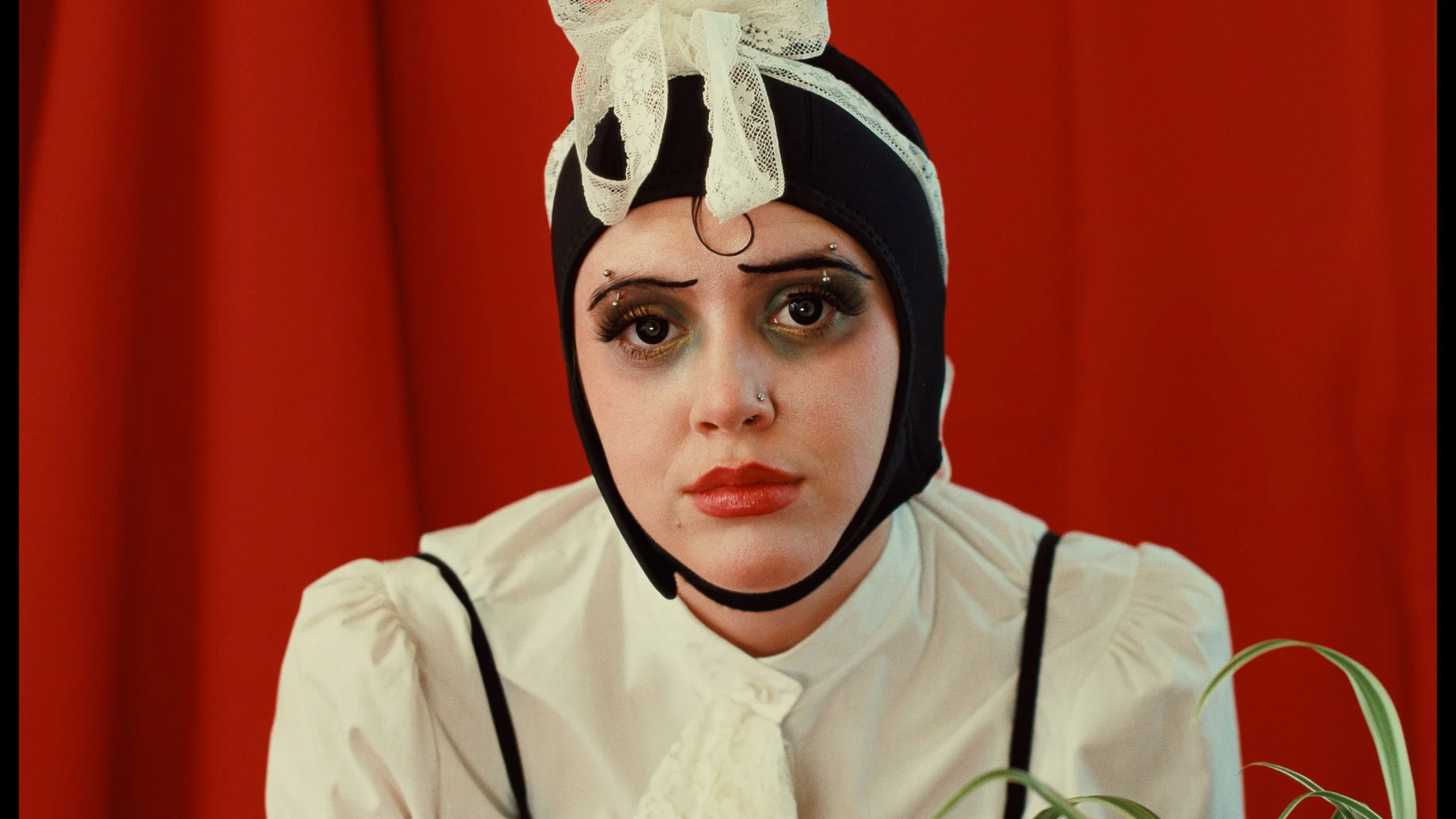 Woman in mime clothing in front of red curtain