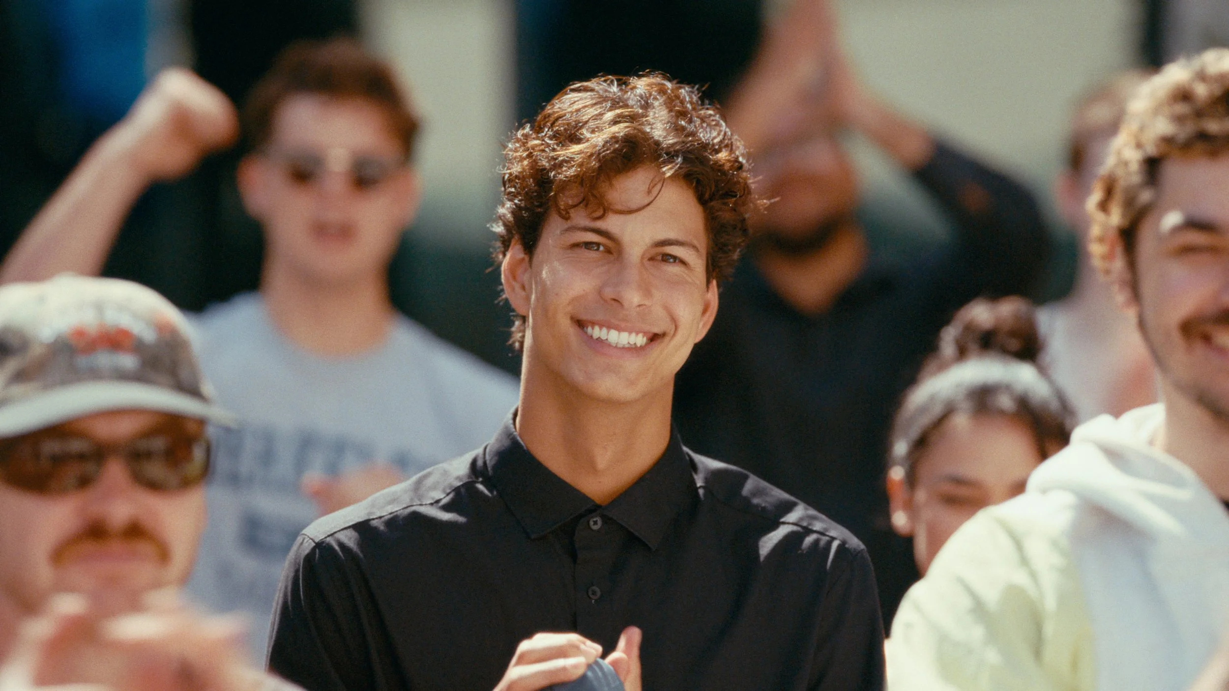 Man in crowd smiling and applauding