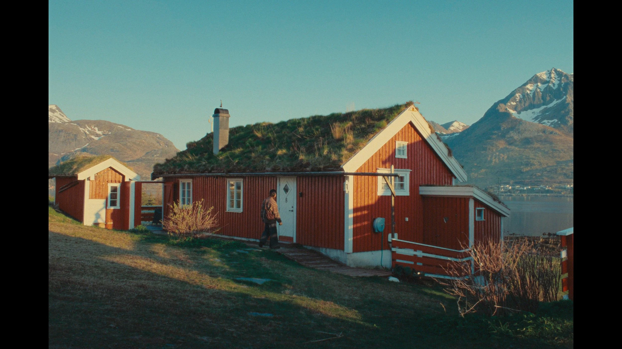 Man walking up to red house in the mountains