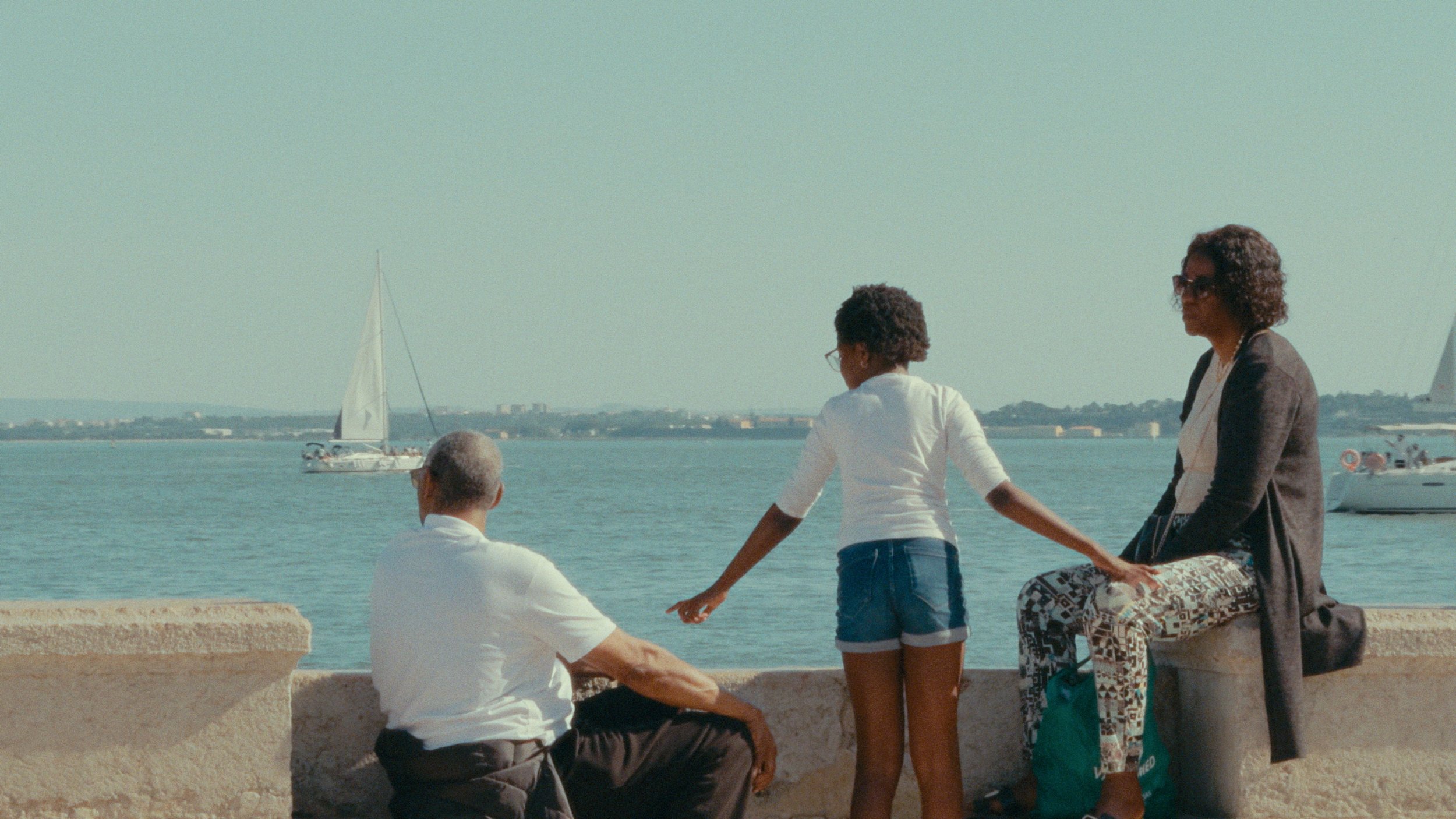 Family watching sailboats by the water