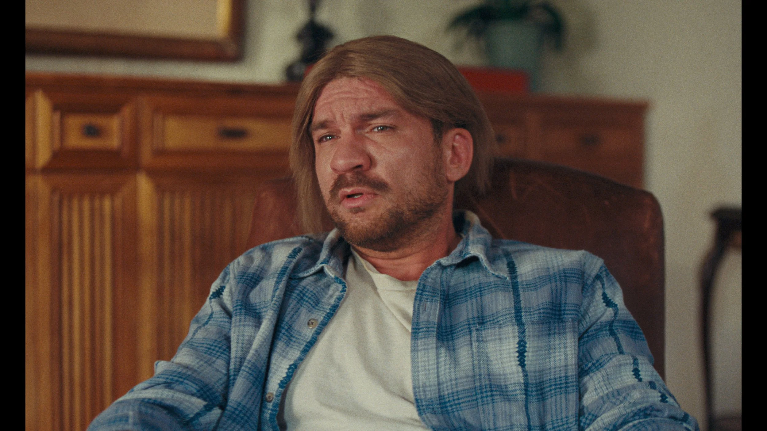 Man in blue shirt sitting in chair, warm cinematic film color grade