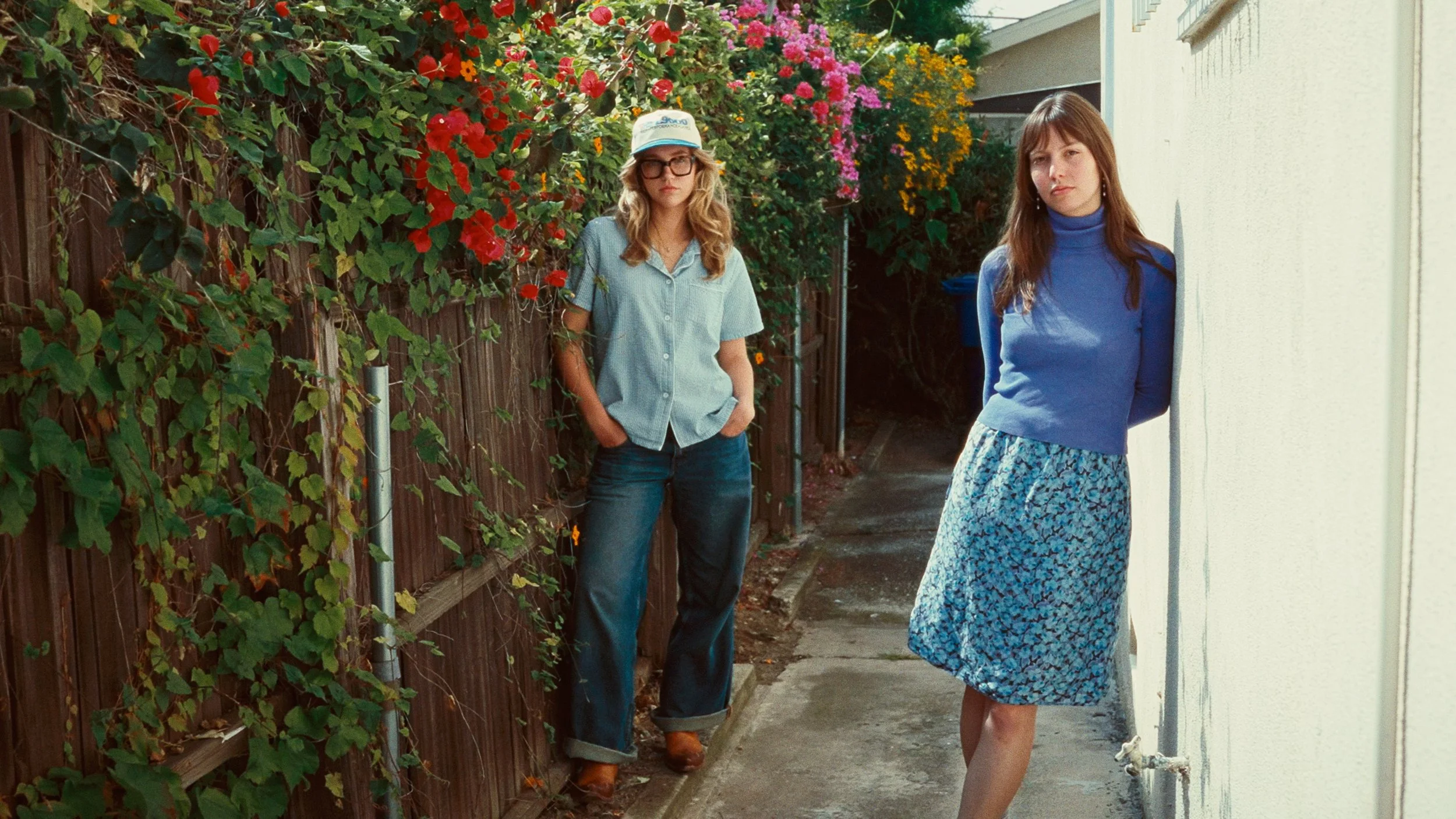 Two women standing next to vines and flowers