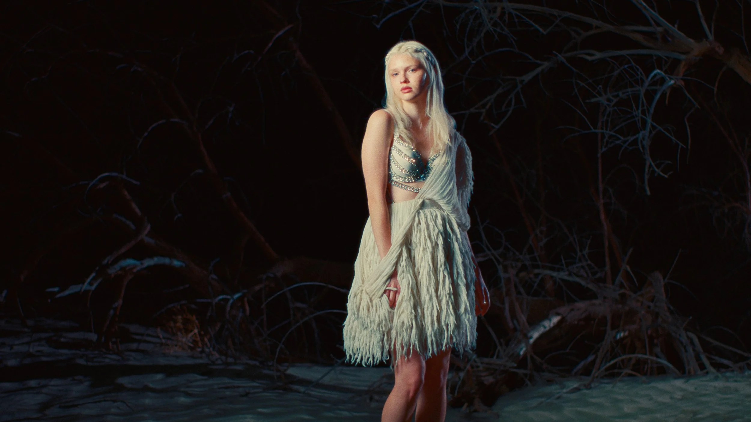 Woman in white dress in dark forest with cinematic lighting