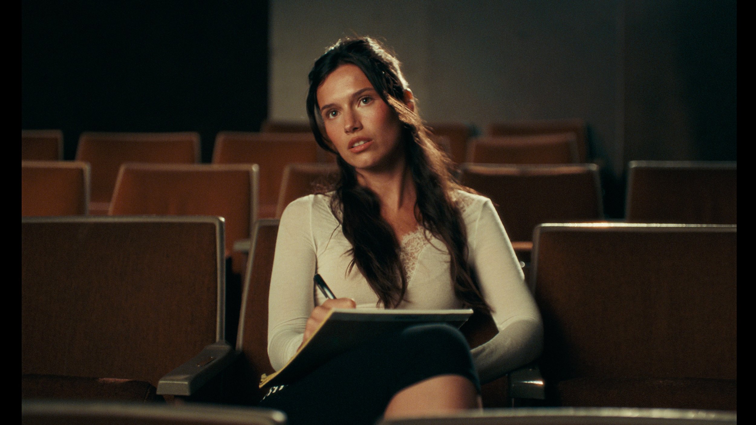 Woman sitting in an empty theater with warm lighting and vintage film emulation color grade