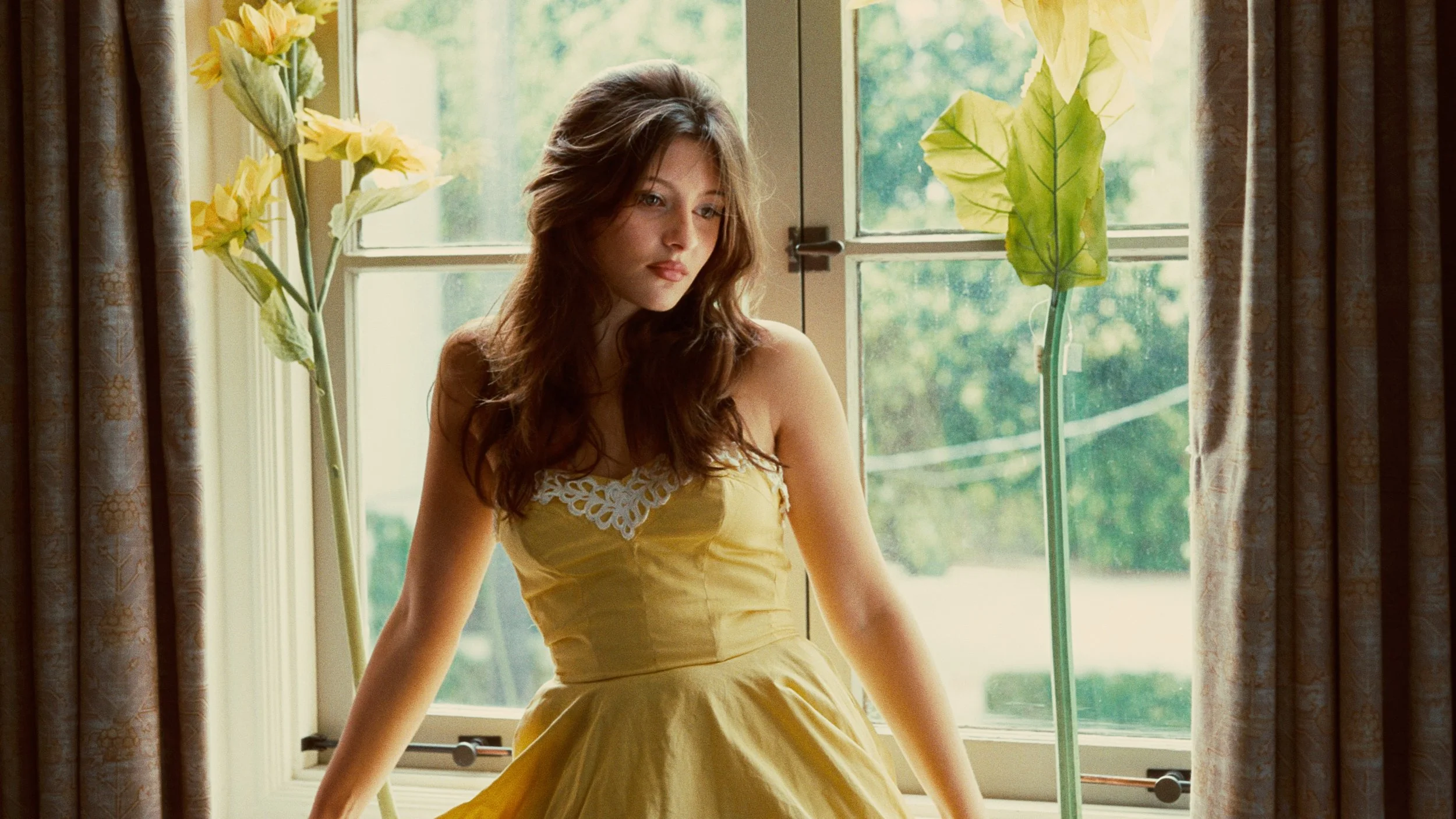 Young woman in yellow dress sitting in window