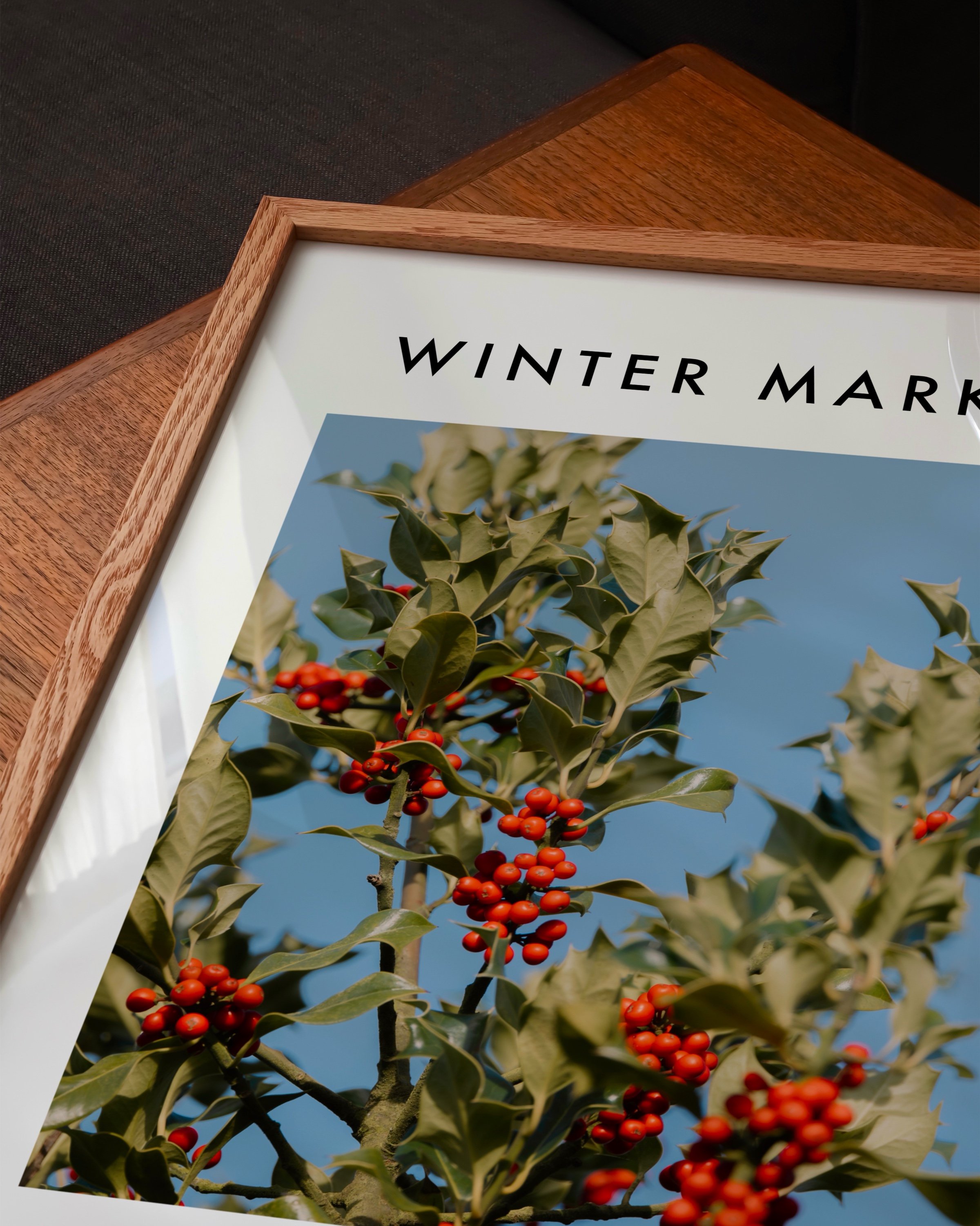 Vibrant photograph of red holly berries with green leaves set against a bright blue sky, perfect for festive holiday decor.