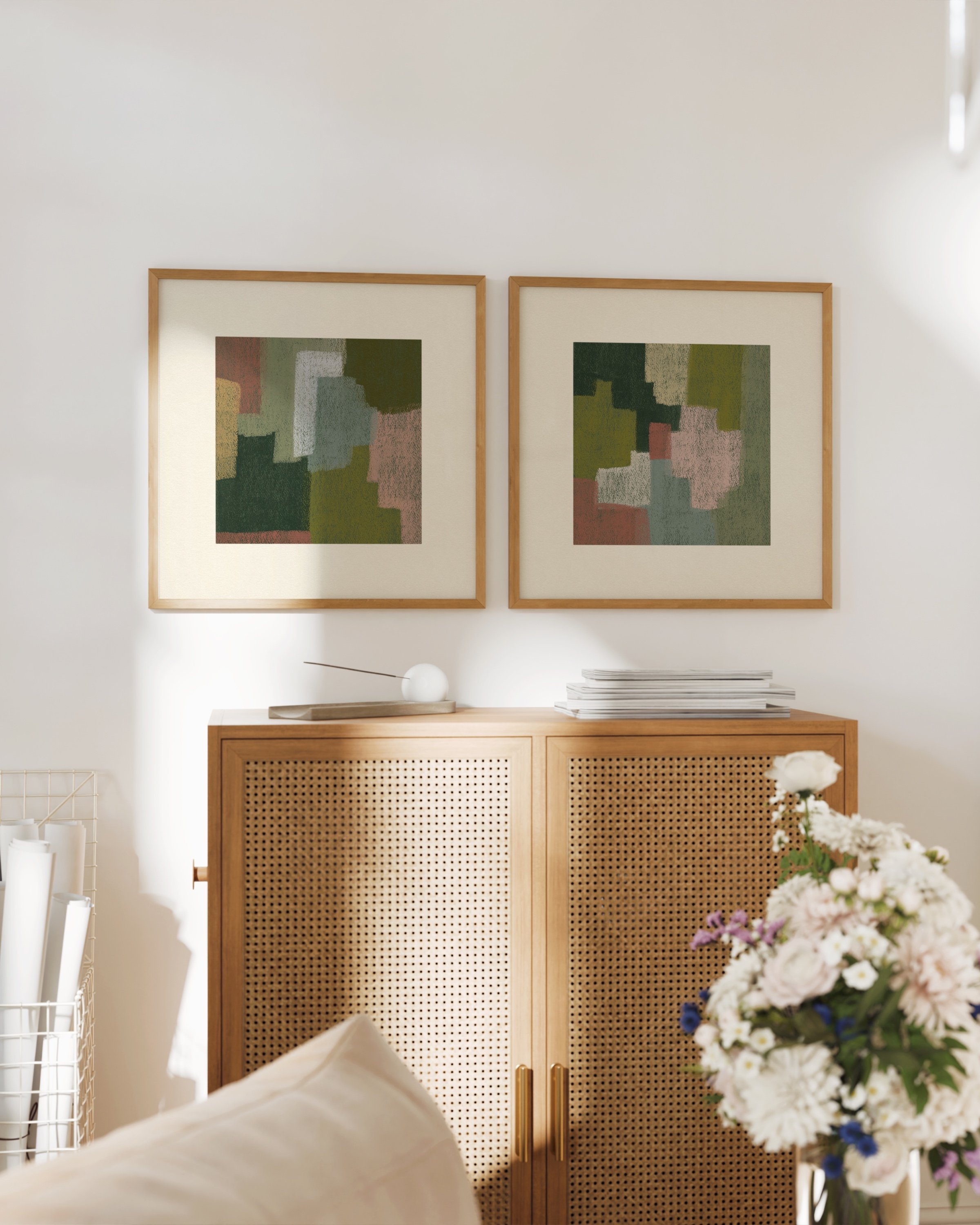 Set of two abstract wall art prints in earthy tones, displayed above a green sofa in a cozy living room.