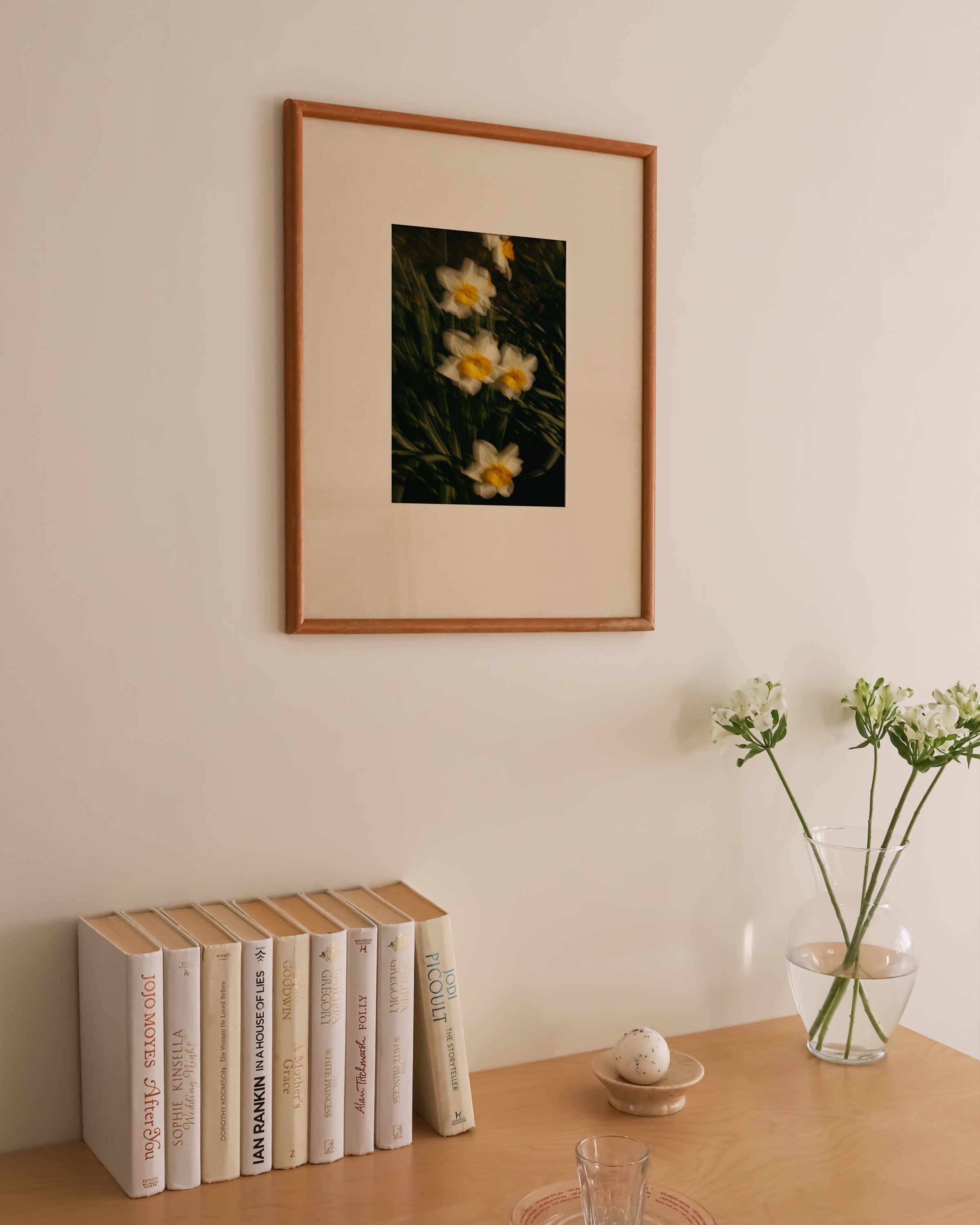 Artistic photo of yellow and white daffodils in soft focus, surrounded by green grass, framed in white.