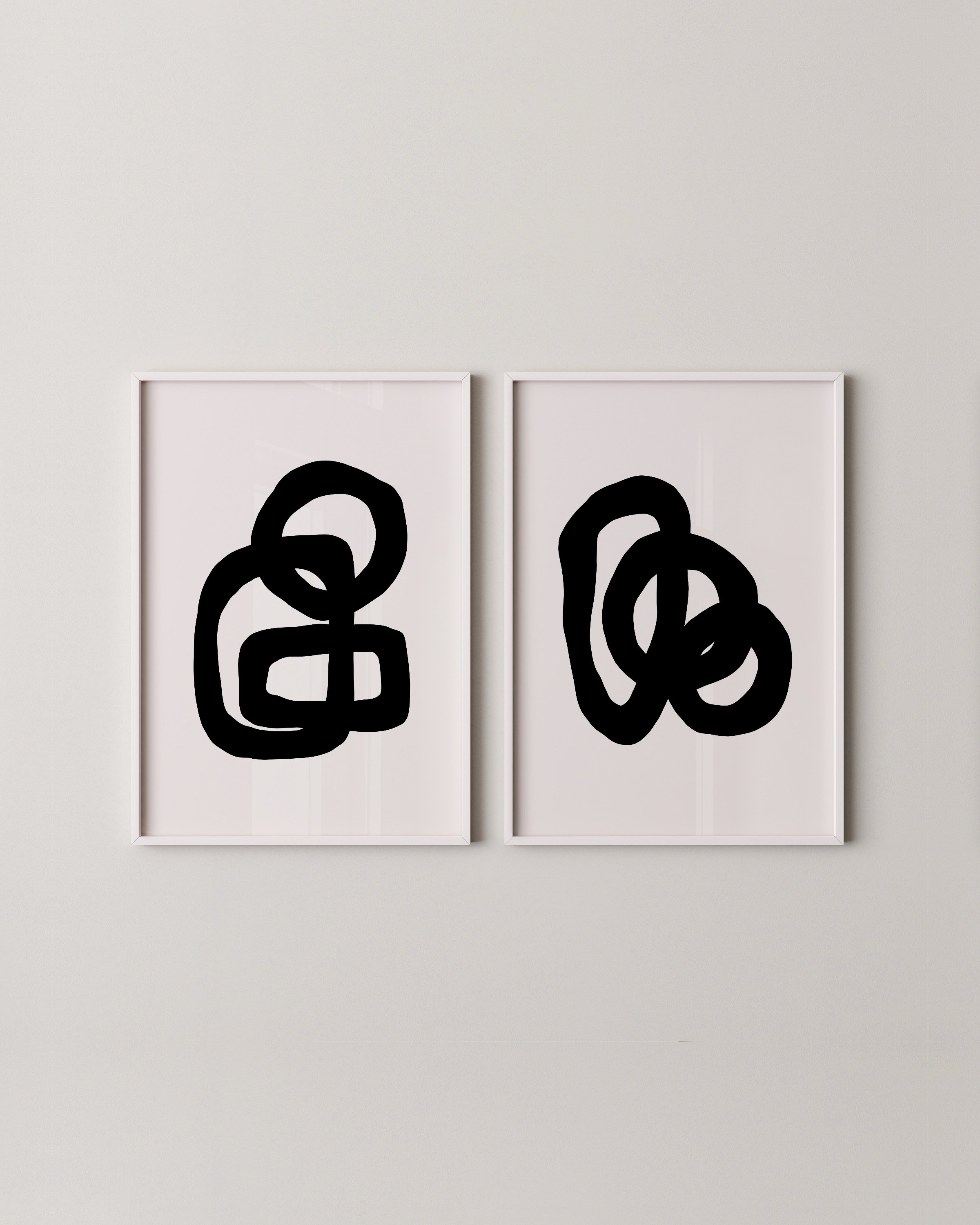 Minimalist abstract art prints featuring bold black loops on white backgrounds, framed in white and displayed as a contemporary art duo.