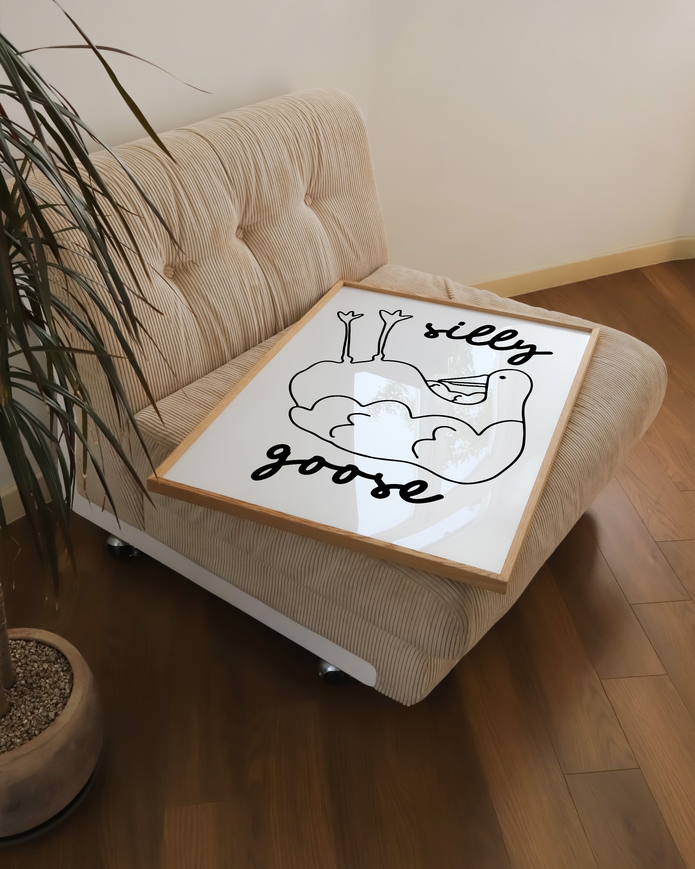 Black and white minimalist art print featuring a hand-drawn goose laying on its back with the words ‘silly goose’ in playful script above and below.