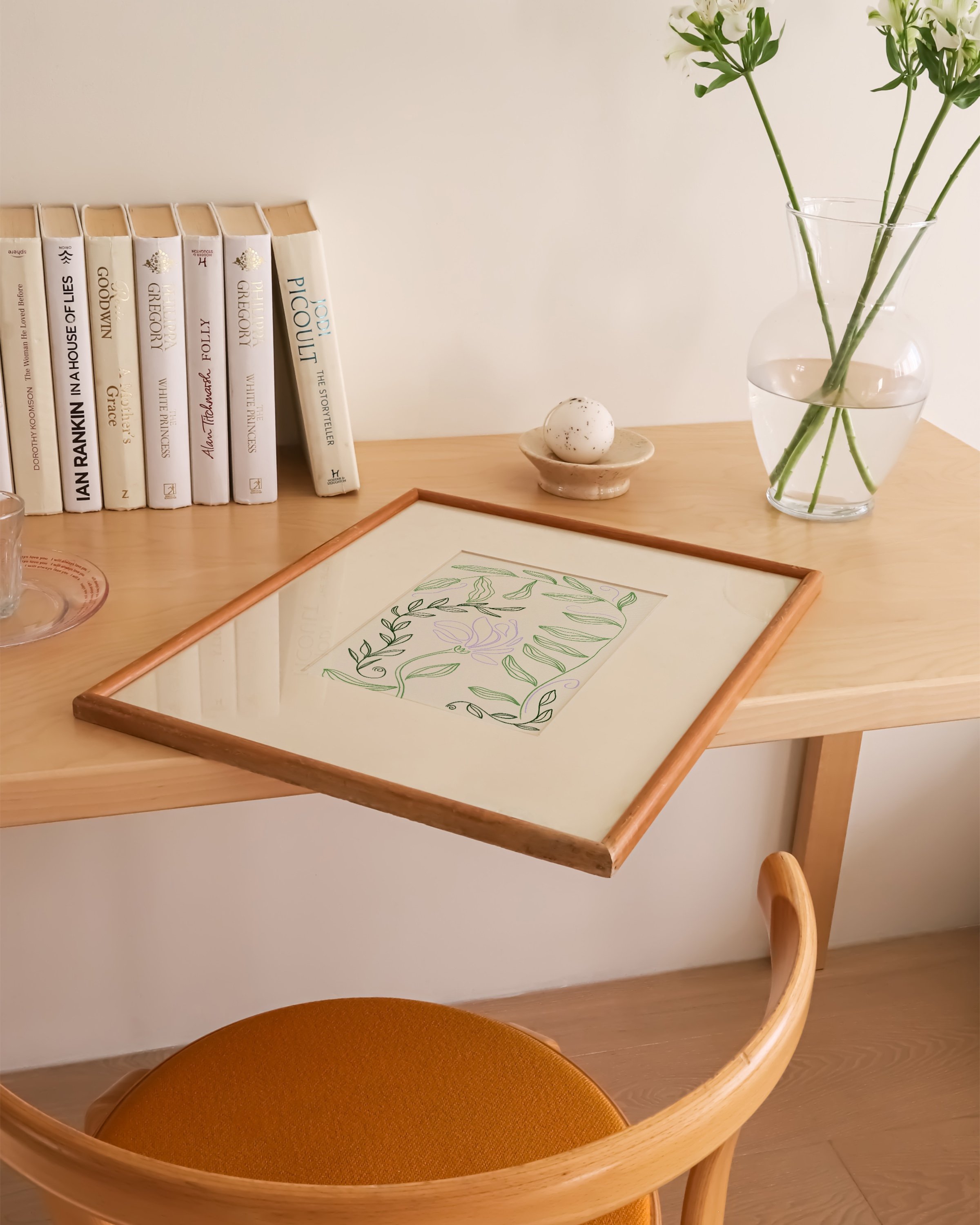Minimalist botanical line drawing with green leafy vines and a delicate lilac flower on a beige background in a white frame.