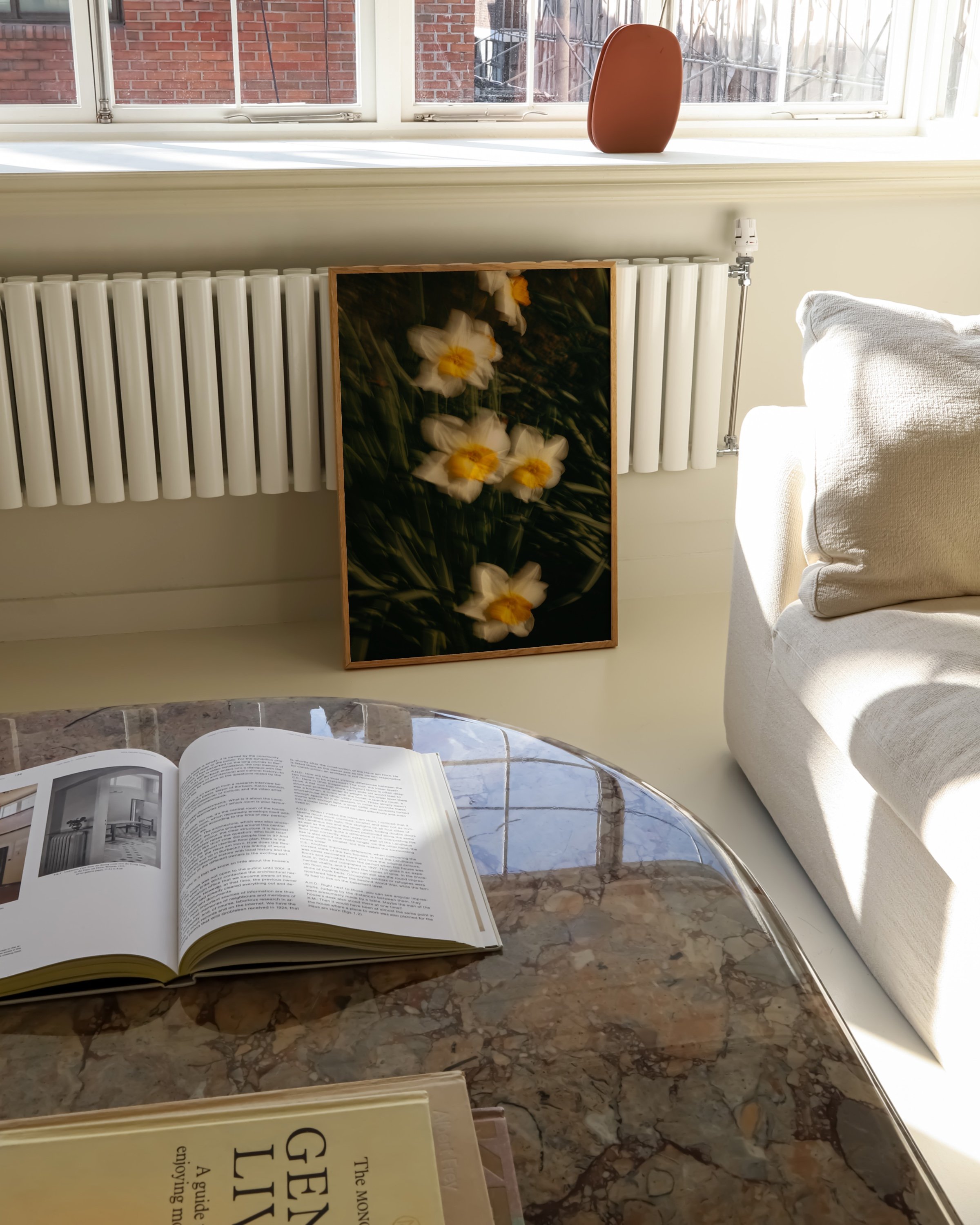 Artistic photo of yellow and white daffodils in soft focus, surrounded by green grass, framed in white.