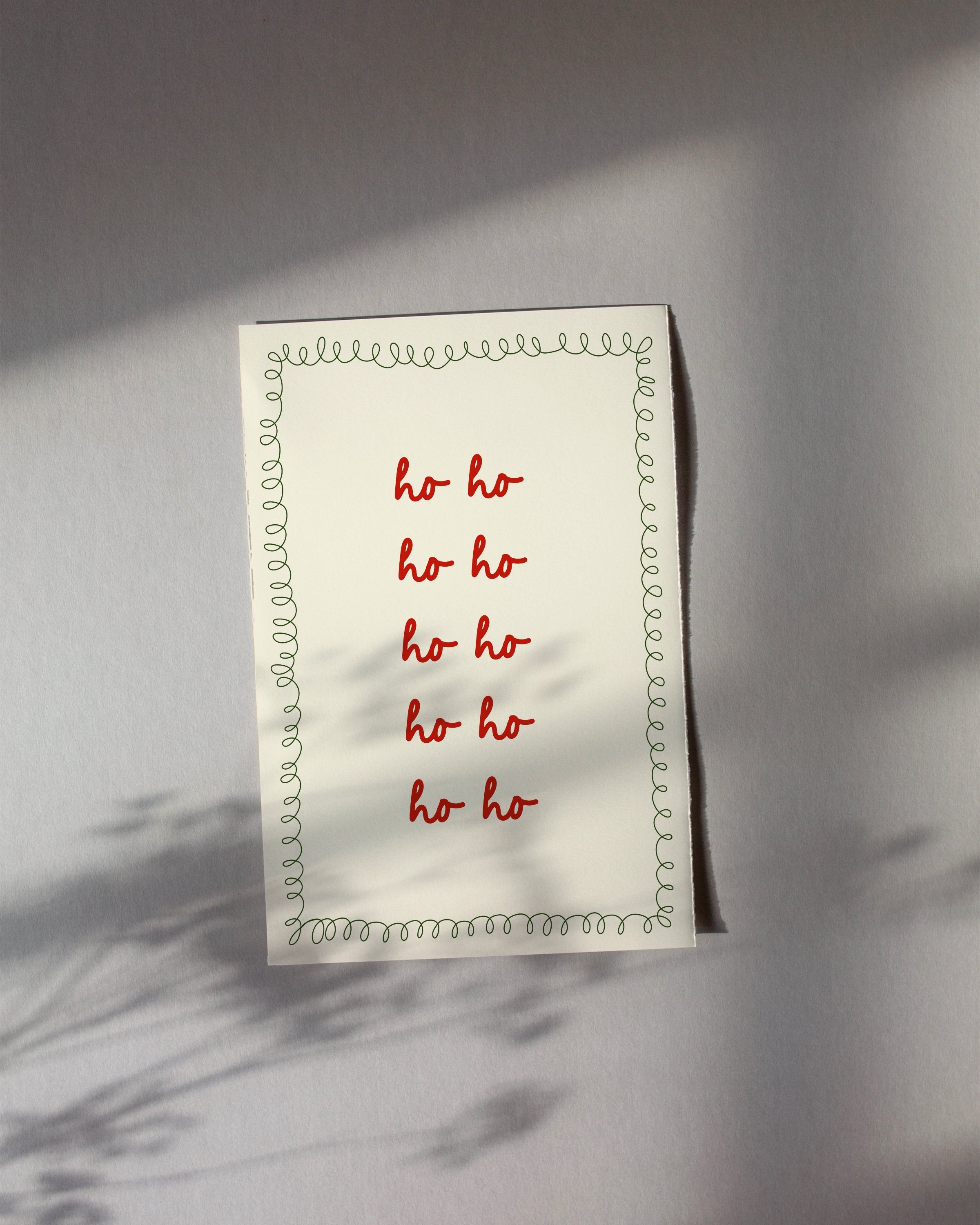 Christmas printable art with repeated red ‘Ho Ho Ho’ text in a handwritten style, framed by a green squiggle border on a beige background.